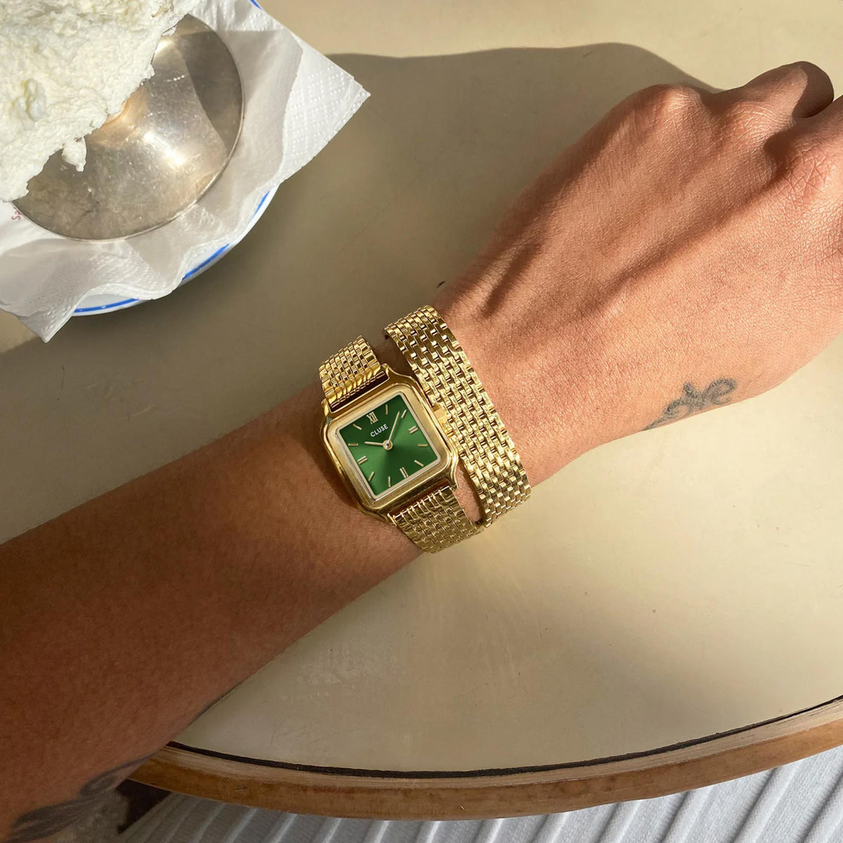 Gold-tone wristwatch with green dial on a metal mesh bracelet strap