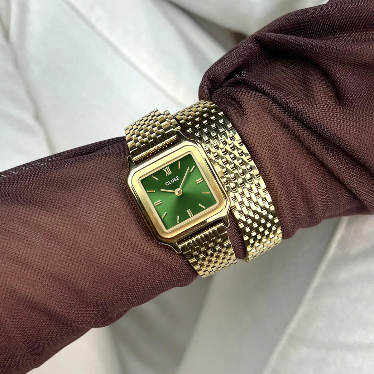 Gold-tone watch with green dial and metal mesh bracelet strap on wrist