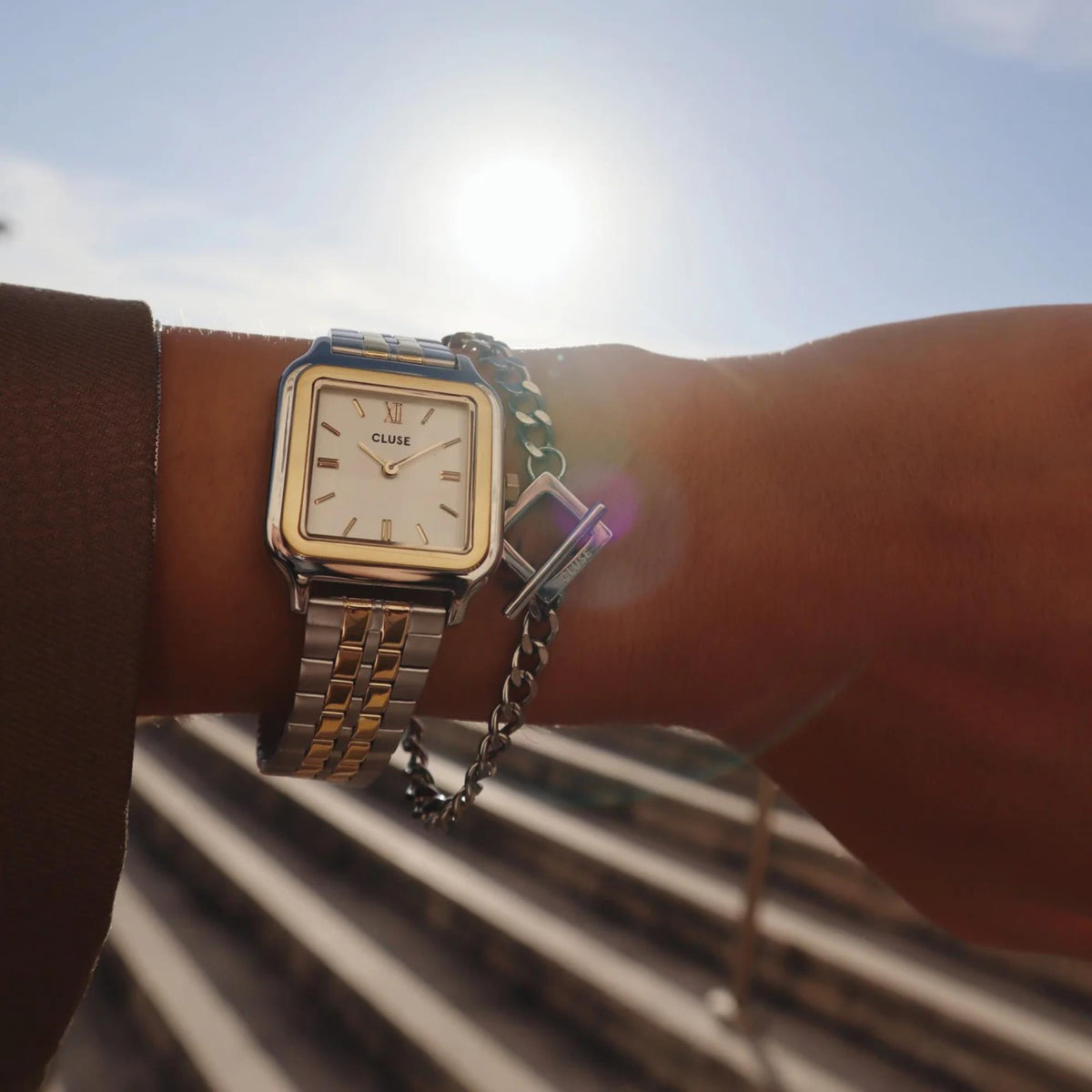 Square two-tone watch on wrist with white dial and gold-tone indices