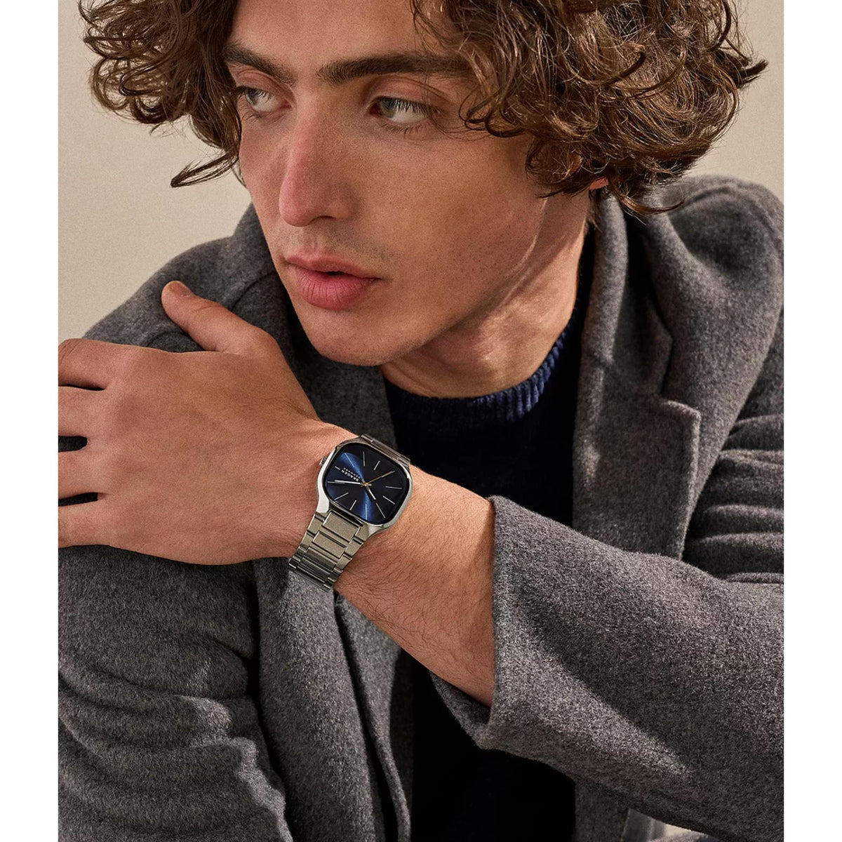 Men's quartz wristwatch with blue dial and silver steel bracelet, close-up on wrist