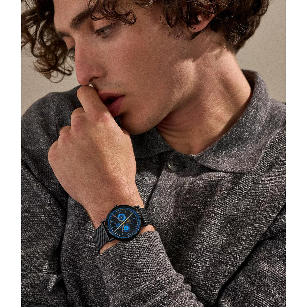 Men's wristwatch on wrist with dark blue dial and black mesh strap