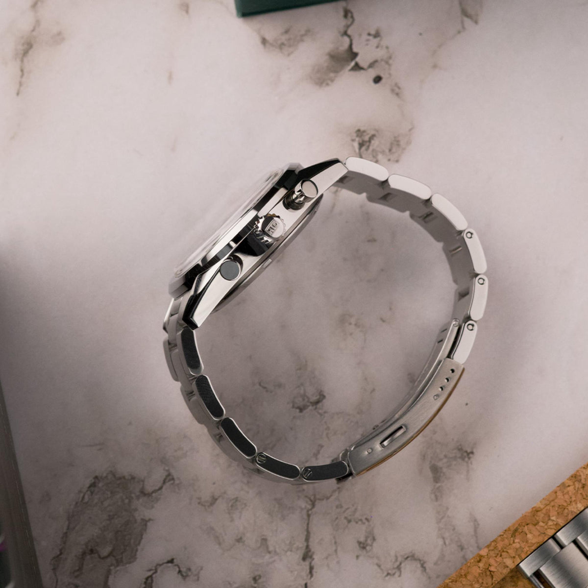 Men's steel chronograph watch case and bracelet top view with clasp and links