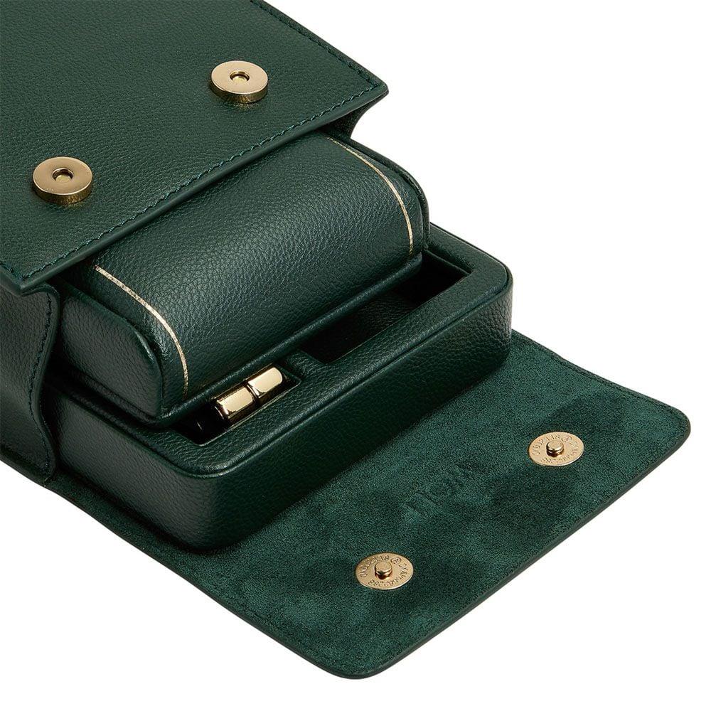 Close-up of green leather watch stand with padded insert and brass snap buttons.