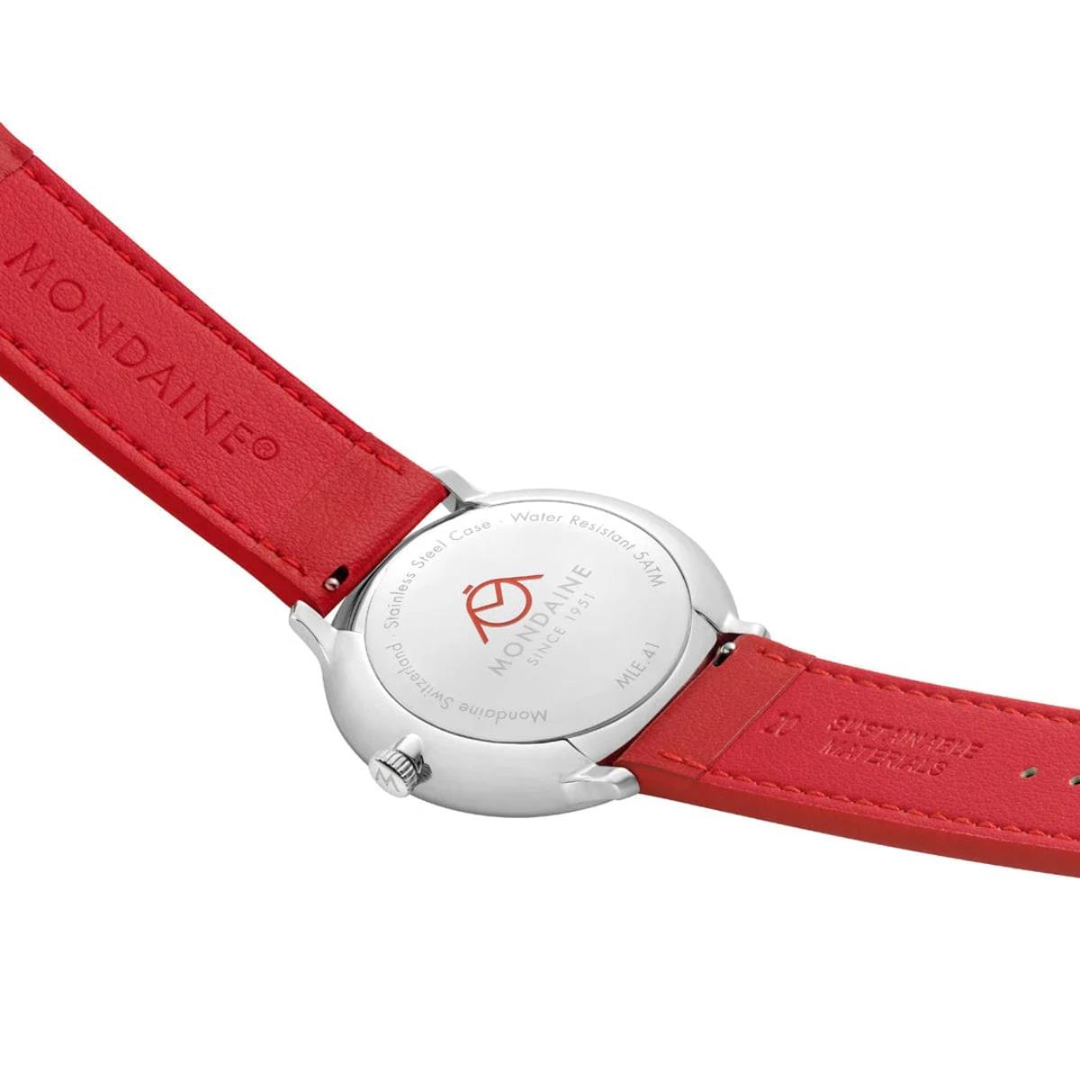 Mondaine Doppio watch caseback detail showing the silver-tone casing, red logo, and red strap lining