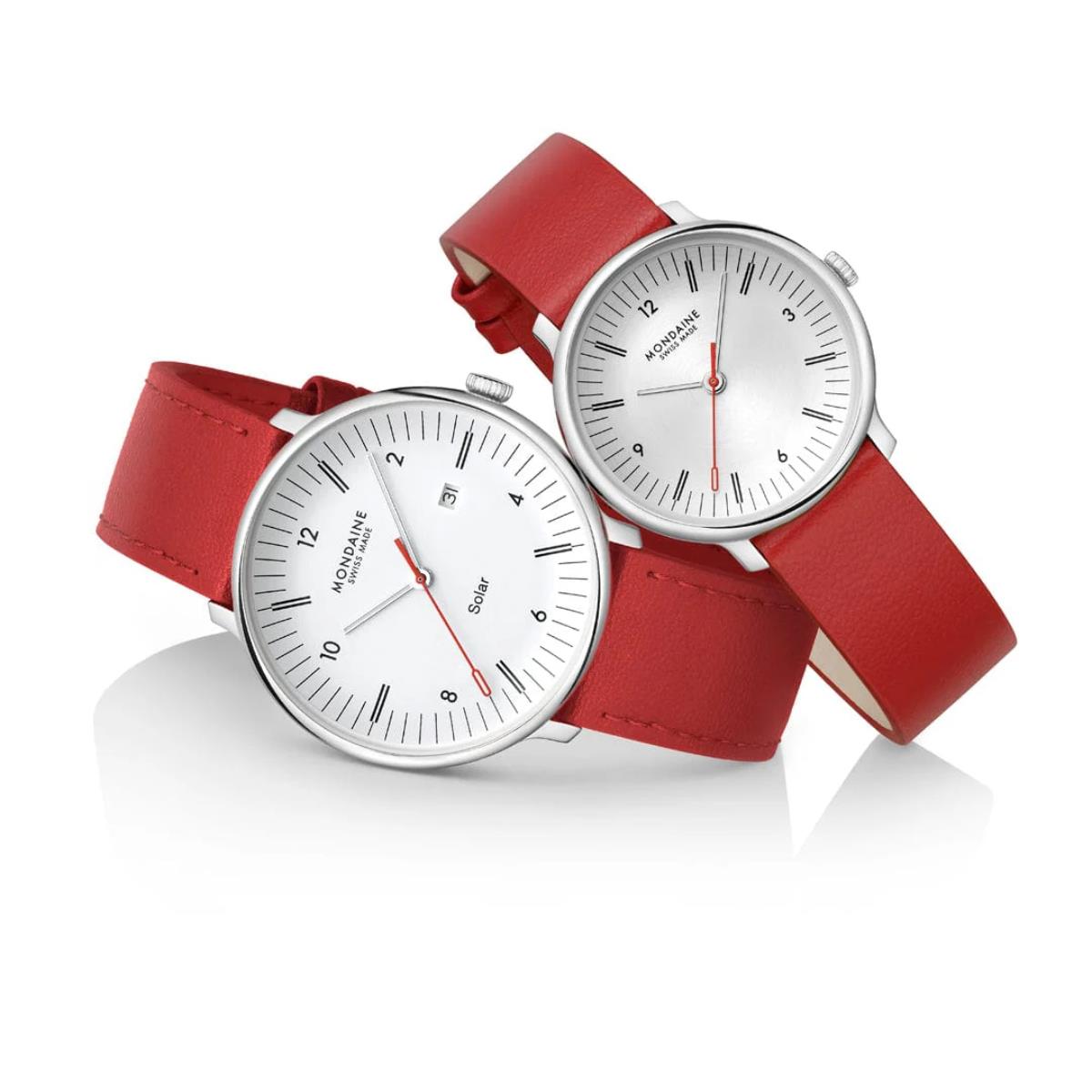 Two Mondaine watches in different sizes with red leather straps overlapping on a white surface