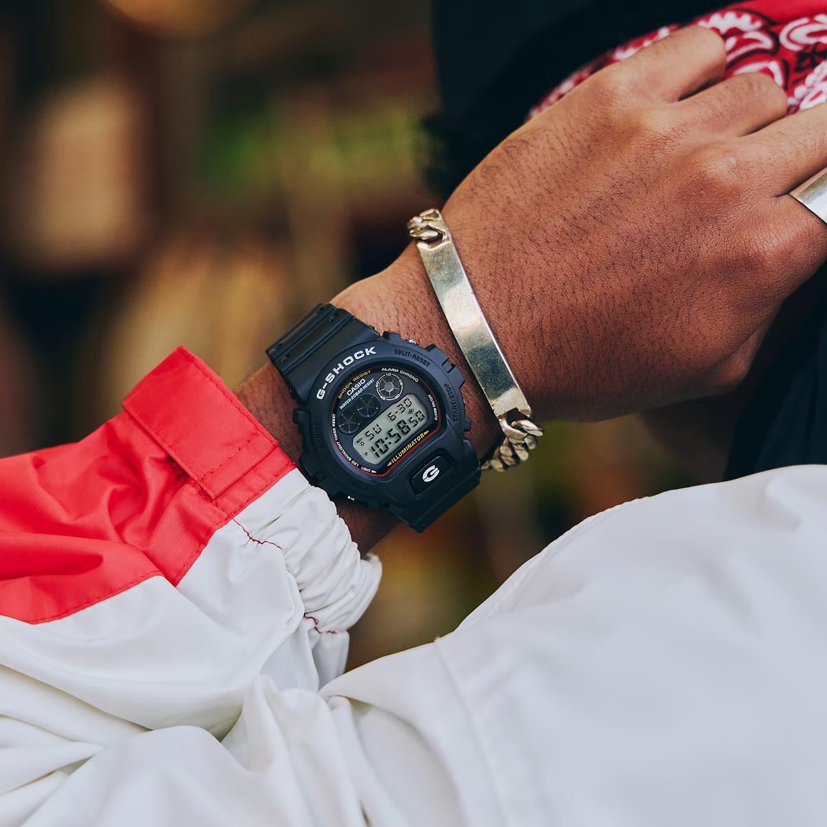 Casio G-Shock 6900 Series DW-6900RL-1ER digital watch worn on a wrist alongside a silver chain bracelet