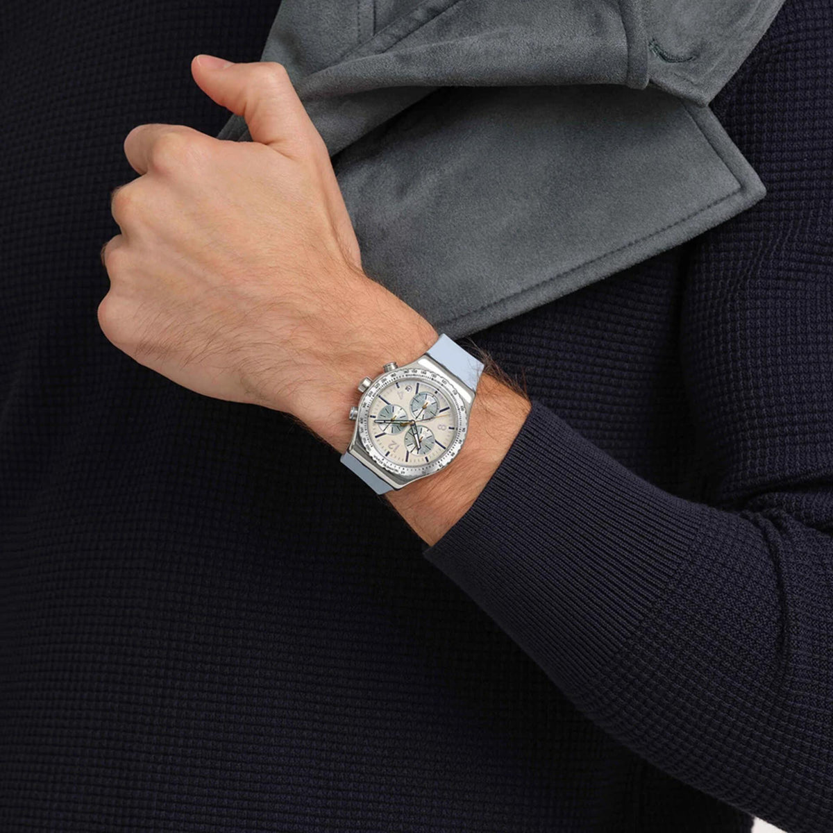 Chronograph watch with silver bezel and blue dial on wrist, light blue rubber strap