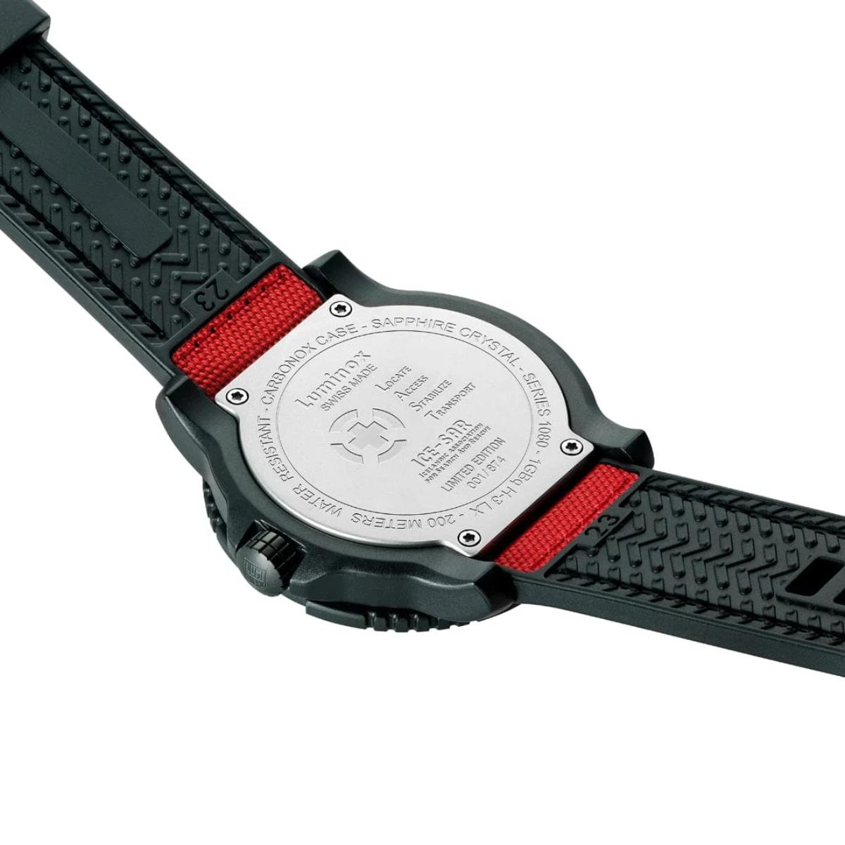 View of the stainless steel caseback of the Luminox ICE-SAR watch, engraved with brand details, showing the black rubber underside of the red textile strap