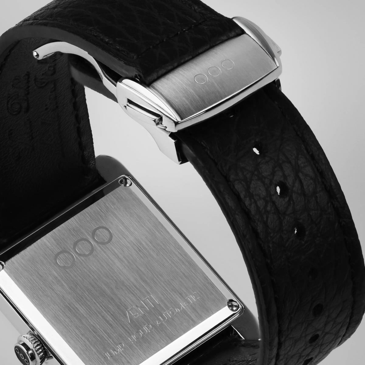 Silver-tone caseback with embossed text on black leather strap and buckle clasp