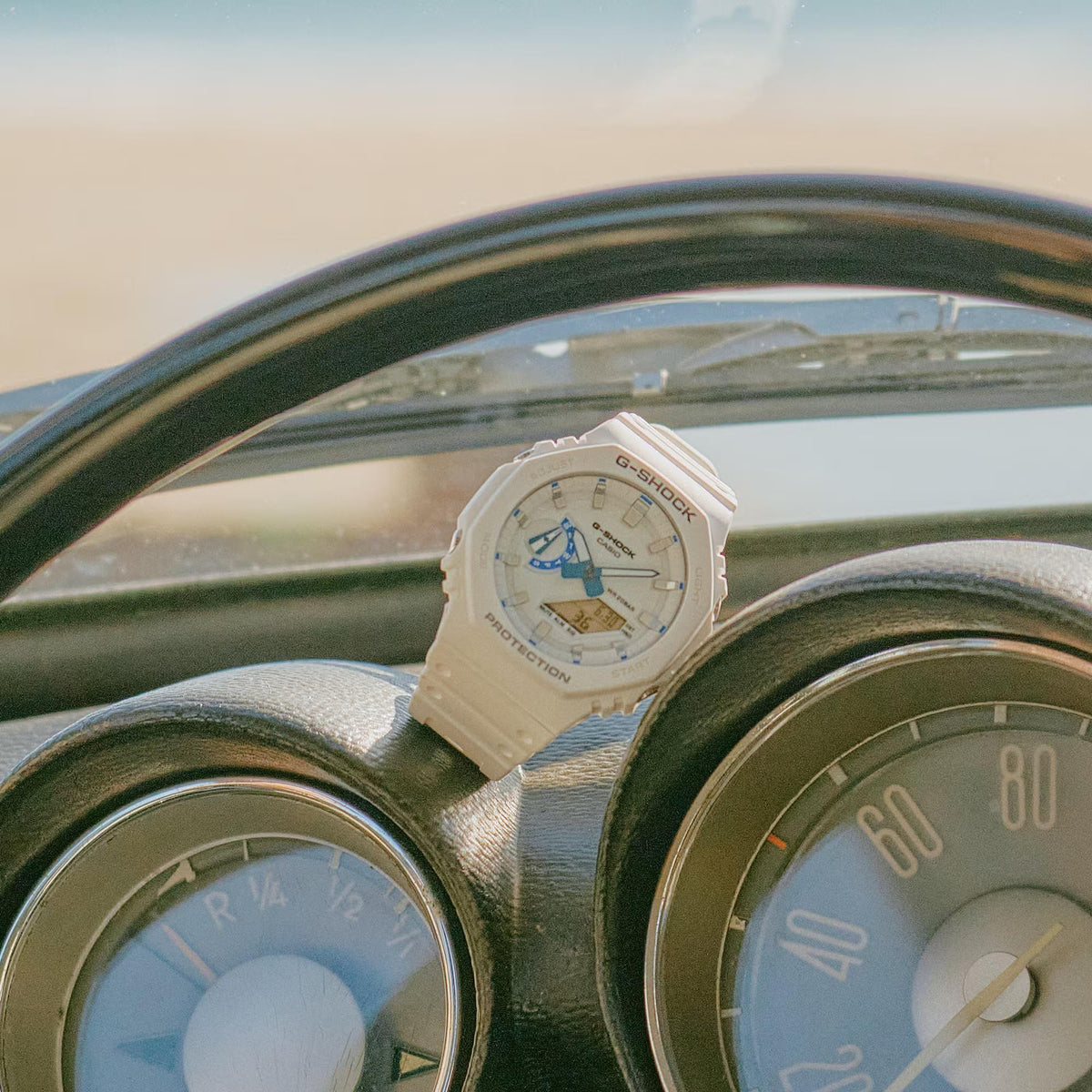 White resin G-Shock watch on dashboard with blue accents and digital indicators