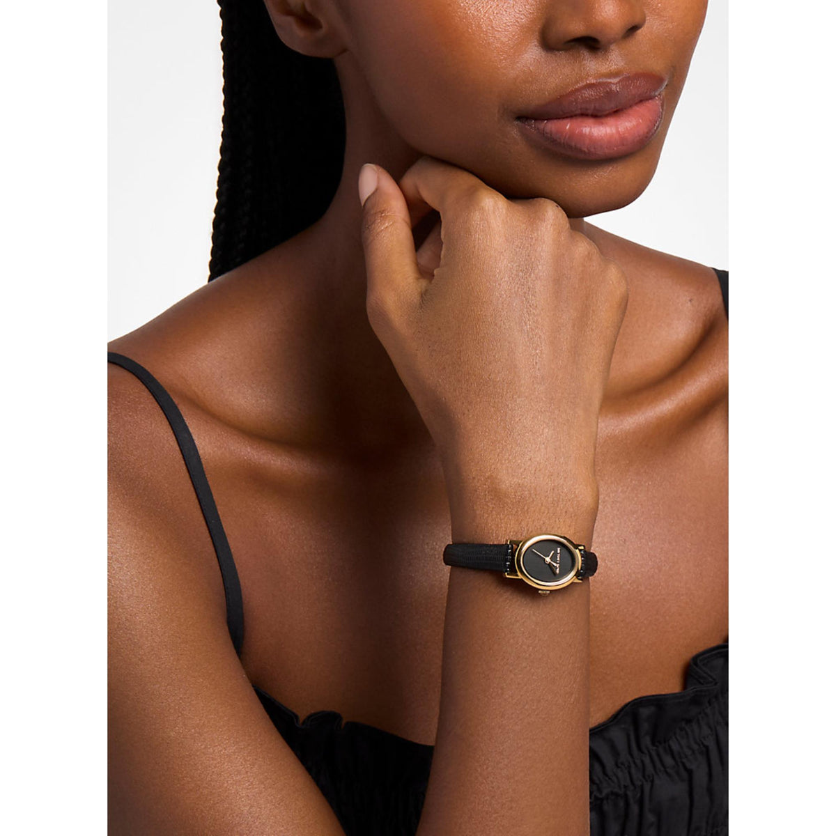 Women’s gold-tone watch on black embossed leather strap worn on wrist