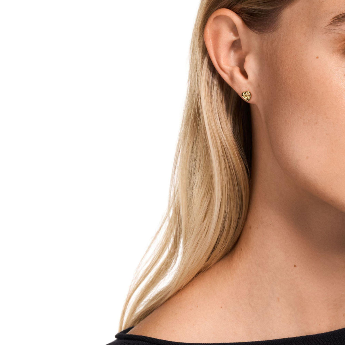 Gold-tone knot stud earrings on model's ear, small twisted round studs