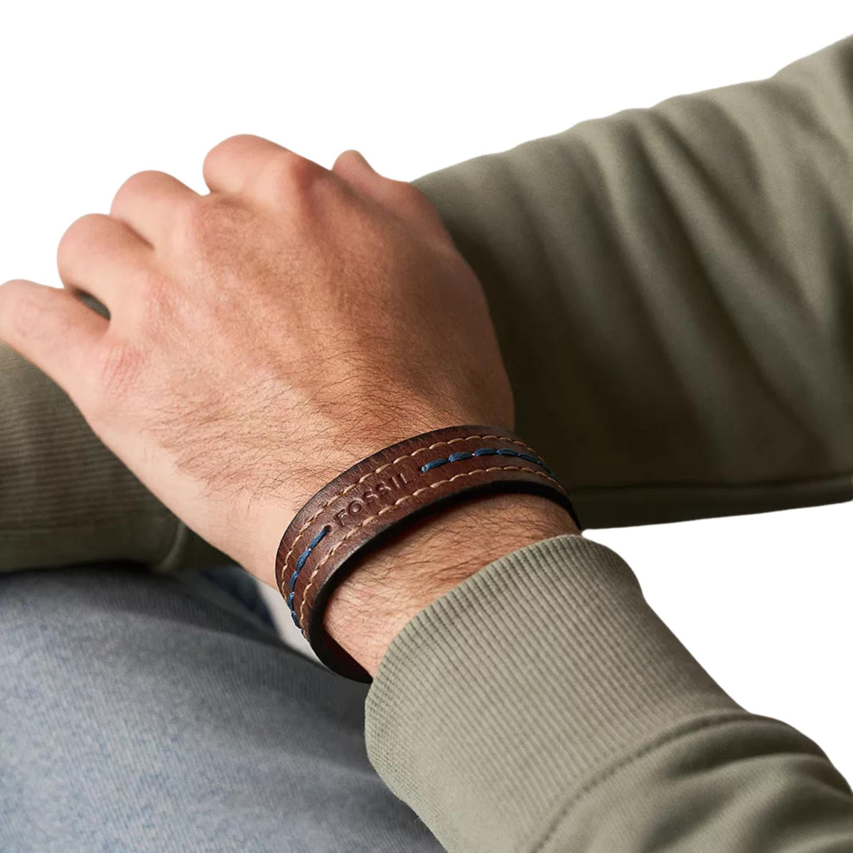 Brown leather strap bracelet on wrist with blue stitch detail