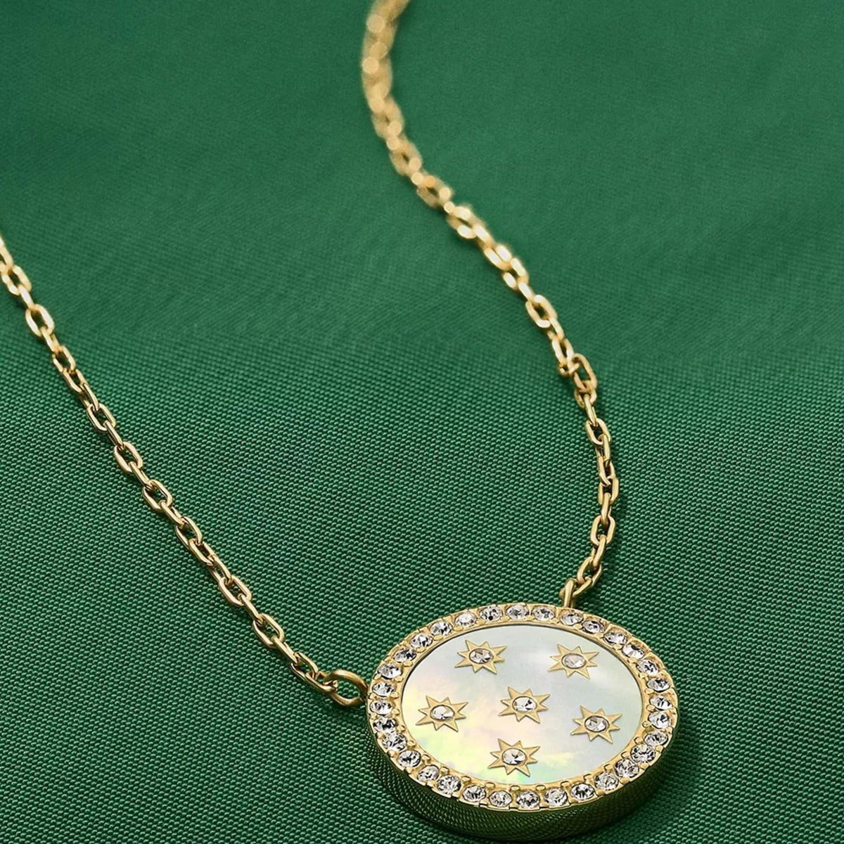 Gold-tone mother-of-pearl pendant necklace close-up: round star disc with crystal border