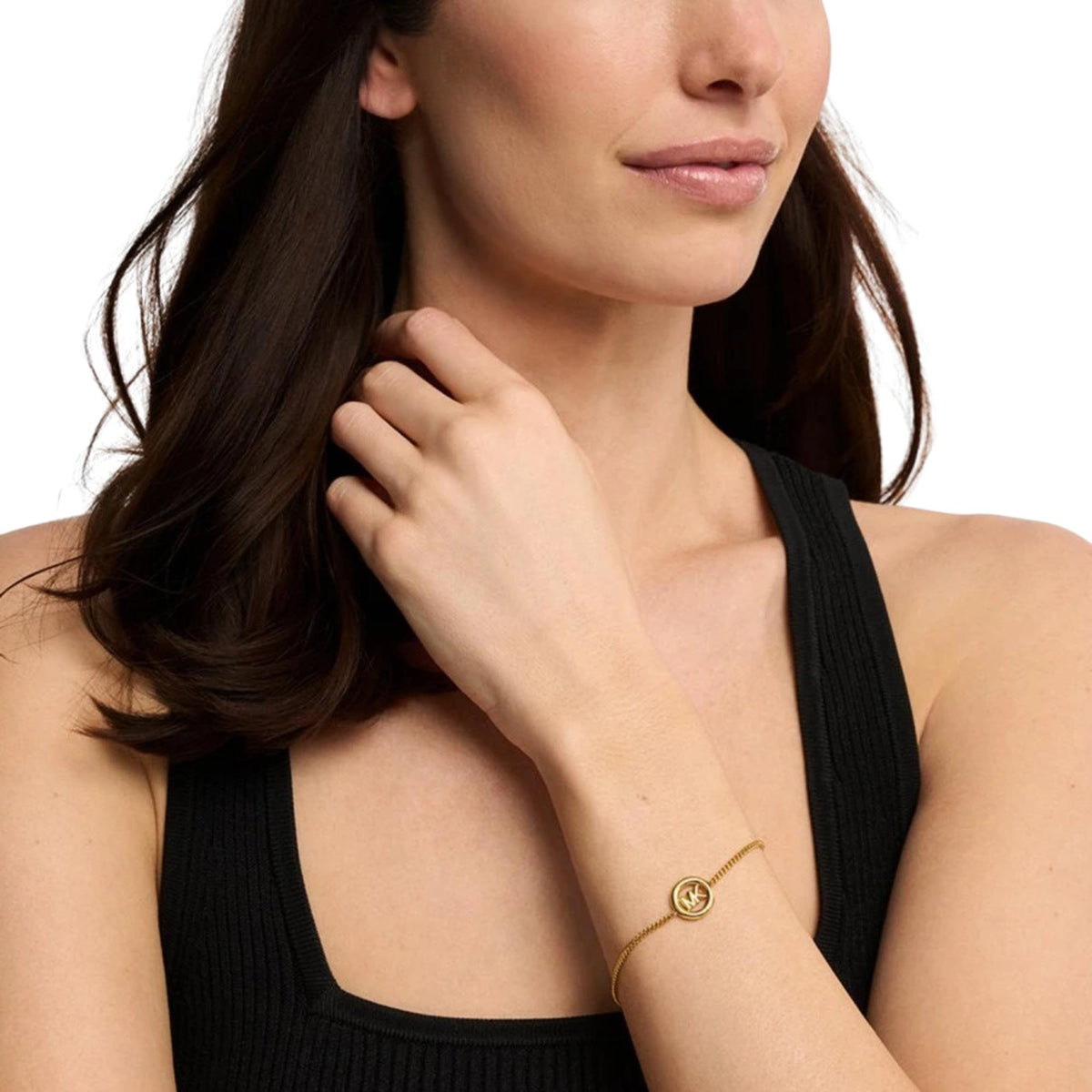 Gold-tone logo bracelet worn on wrist with round MK charm
