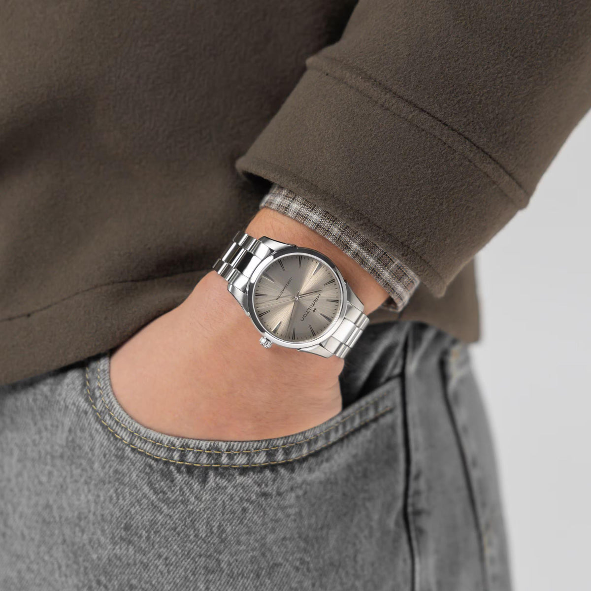 Hamilton Jazzmaster H32461121 quartz watch wrist shot paired with brown jacket and grey jeans showing beige dial