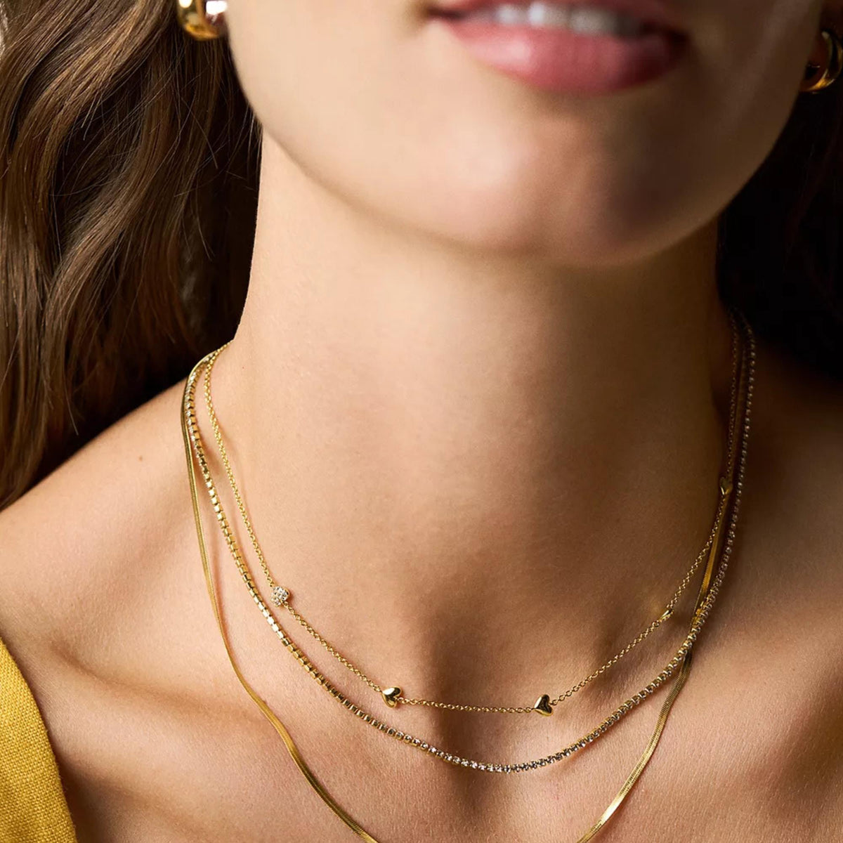 Layered look: gold-tone necklace with small hearts and rhinestone station accents