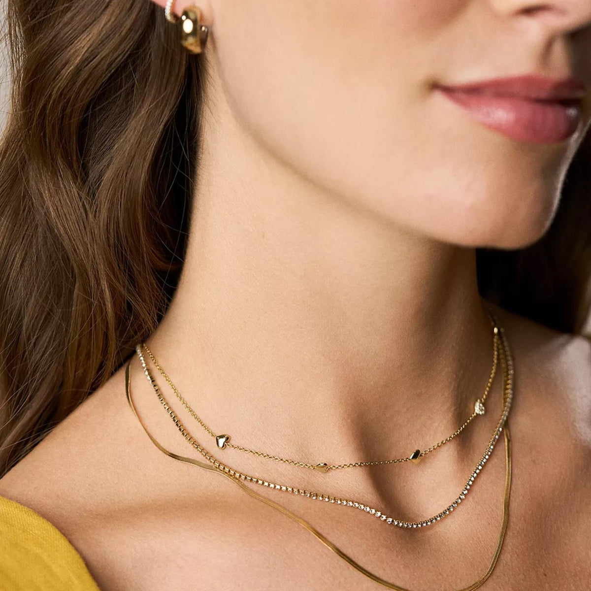 Gold-tone necklace on model with heart charms and rhinestone station details