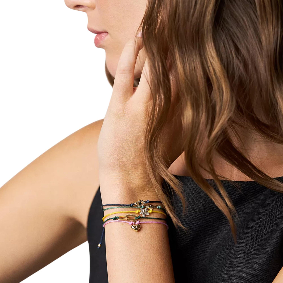 Fossil pink cord bracelet with gold star-and-heart charm on model’s wrist