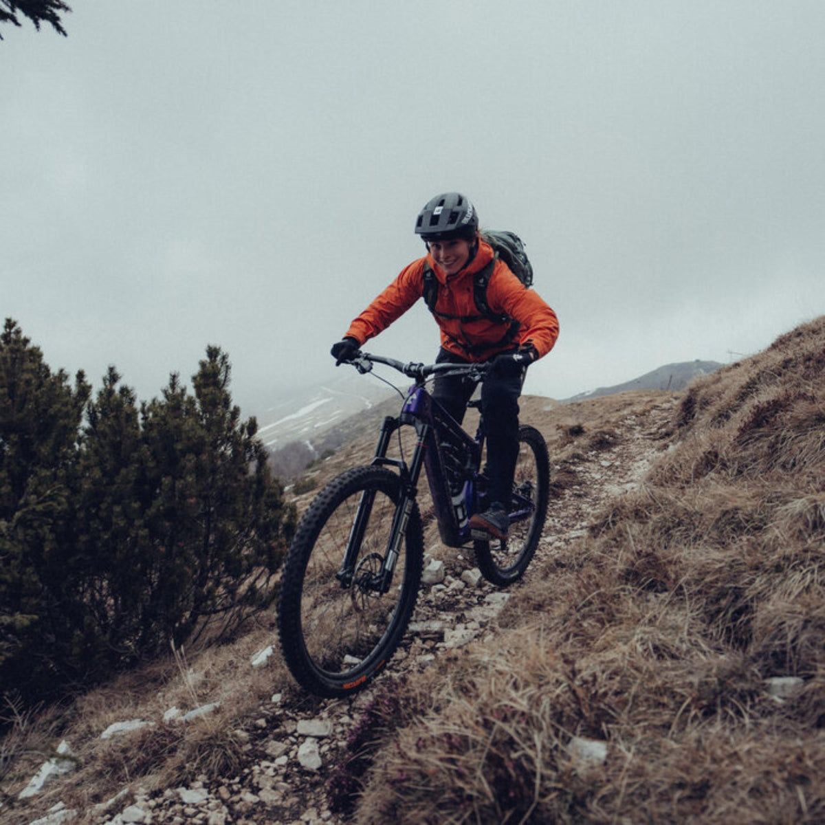 Suunto Vertical Black Ruby SS050865000 action lifestyle view of cyclist riding mountain bike along outdoor trail