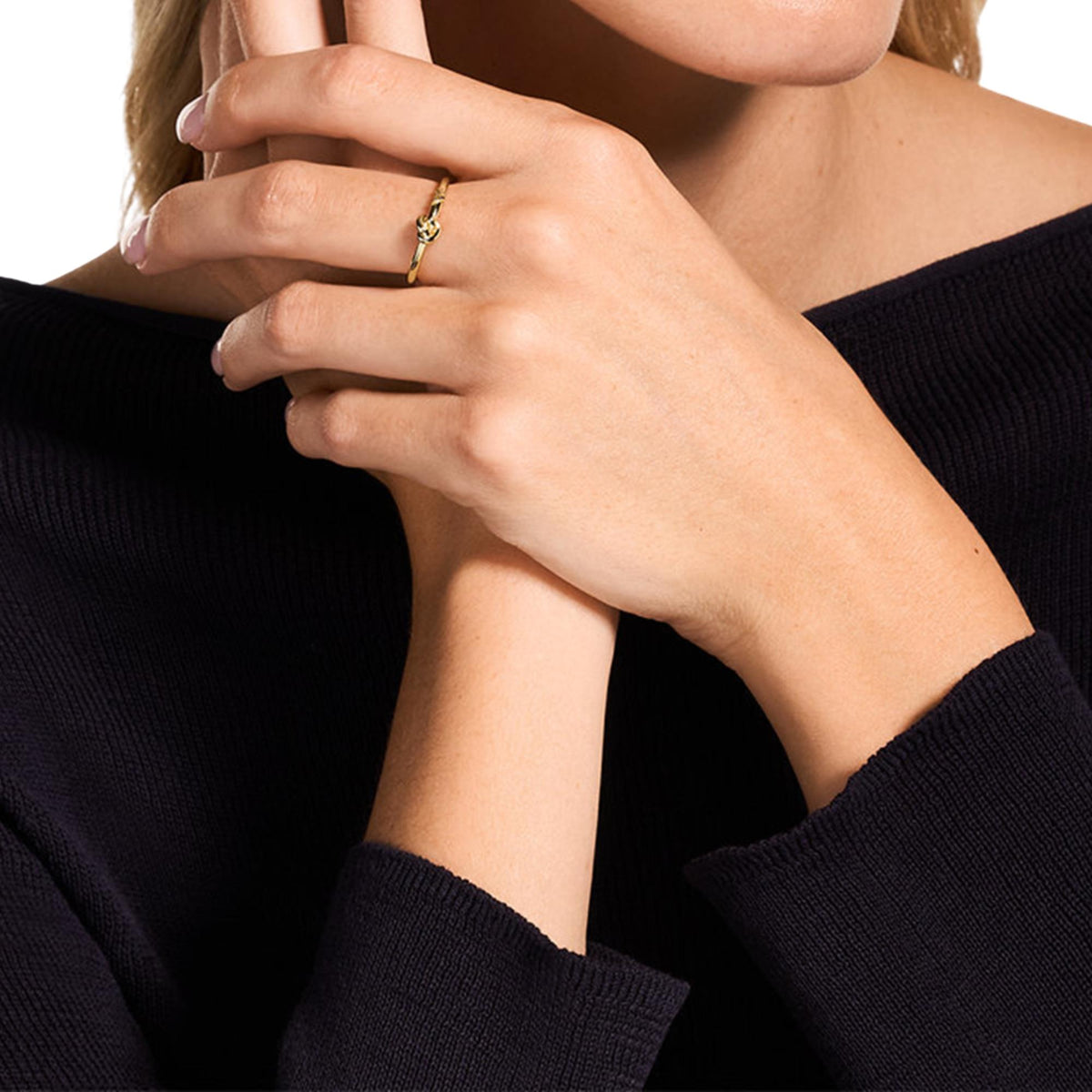 Gold-tone women's ring on finger, sculpted knot and etched logo on band