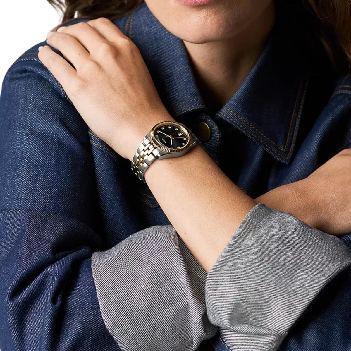 On-wrist view of the Fossil Scarlette ES5458 ladies timepiece displaying the black dial with a two-tone steel bracelet styled with denim clothing