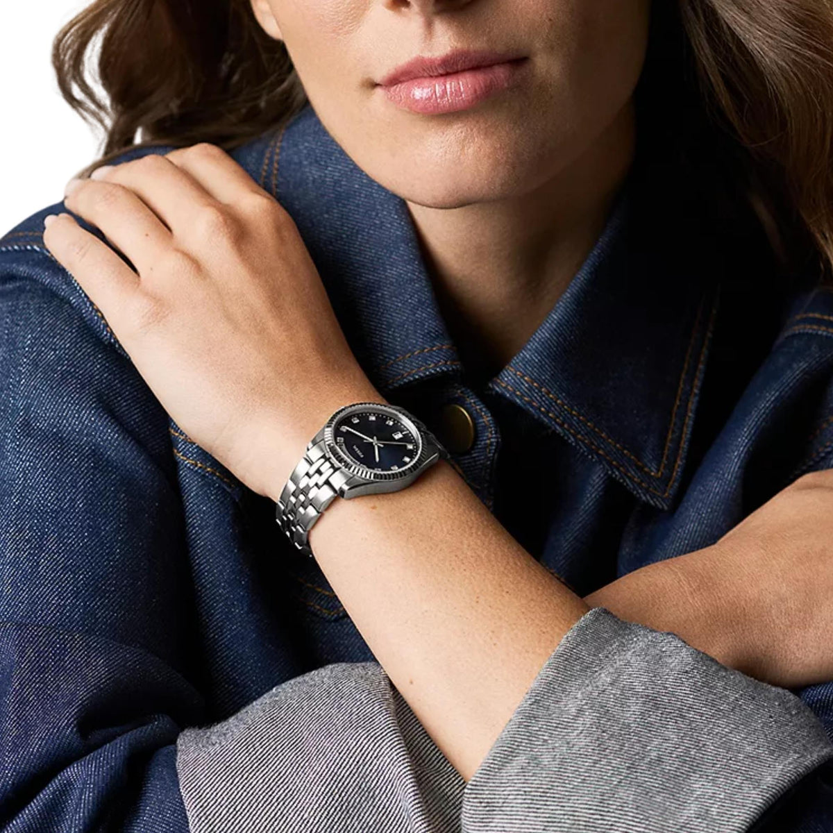 Model styled in a denim jacket, wearing the Fossil Scarlette ES5457 watch with a blue dial and polished steel bracelet