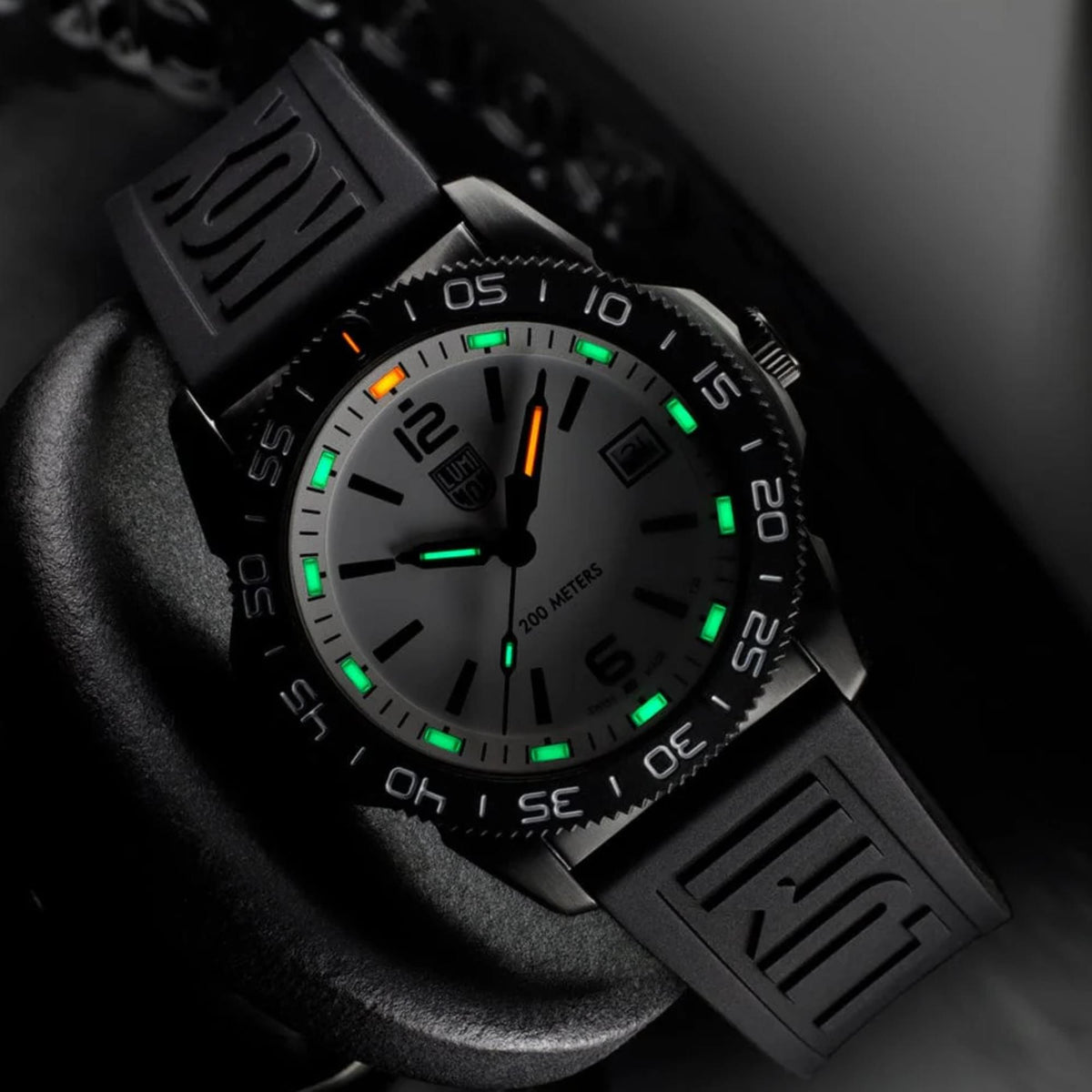 Angled studio shot of the Luminox Pacific Diver XS.3127M in dark lighting, highlighting glowing green and orange tritium tubes