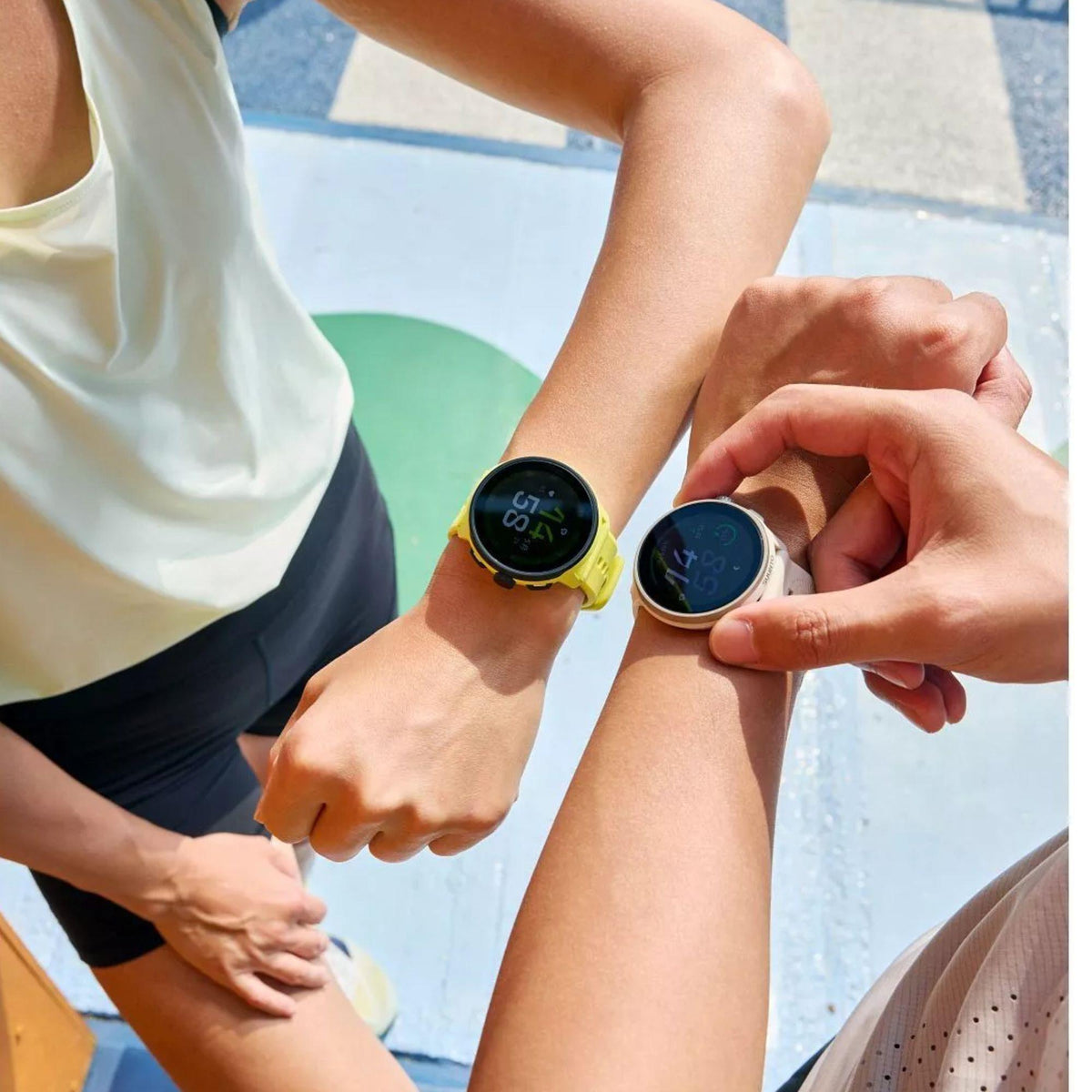 Two runner wrists side-by-side with one wearing a yellow variant and the other wearing the Suunto Run Frost Gray smart watch
