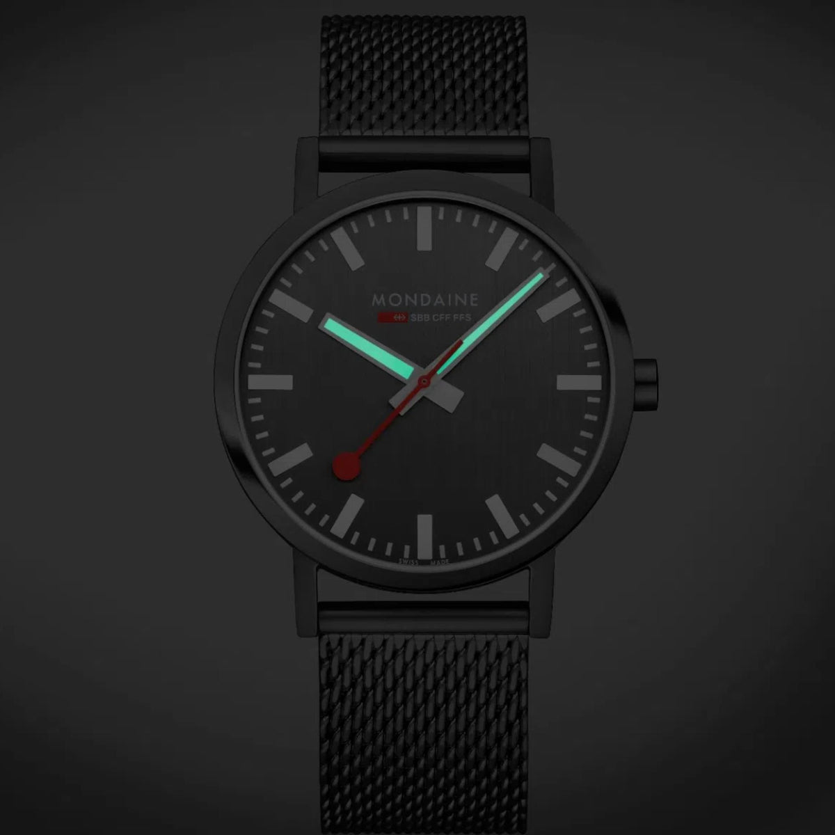 Mondaine Classic watch with dark case, gray dial, red seconds hand, and textured bracelet