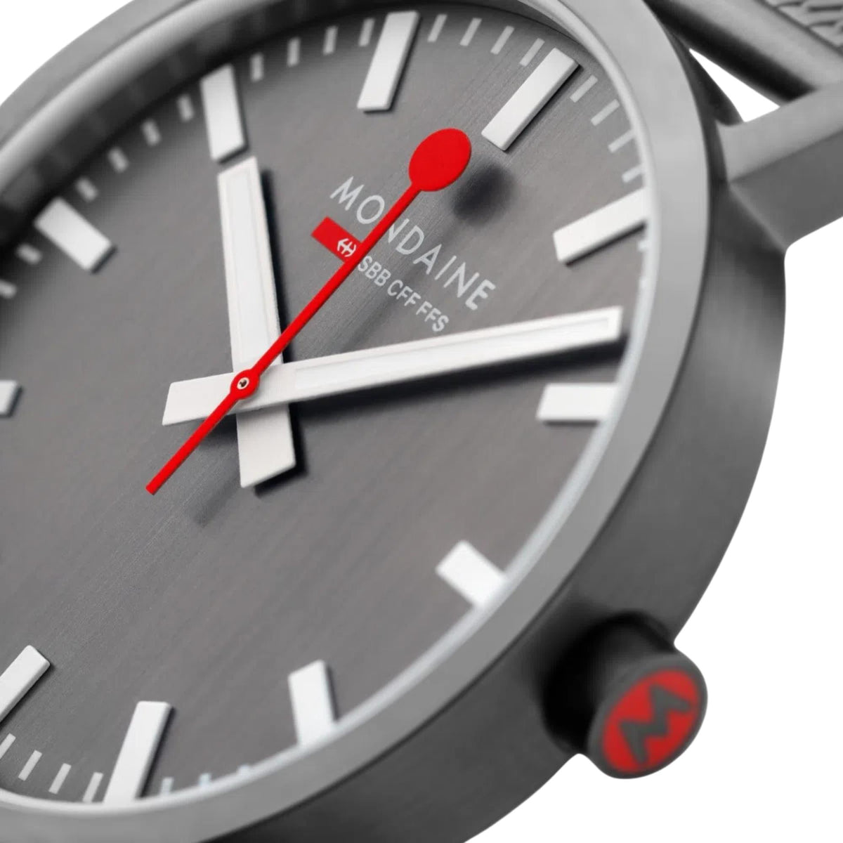 Close-up of Mondaine watch dial with red second hand and hour markers on dark gray face