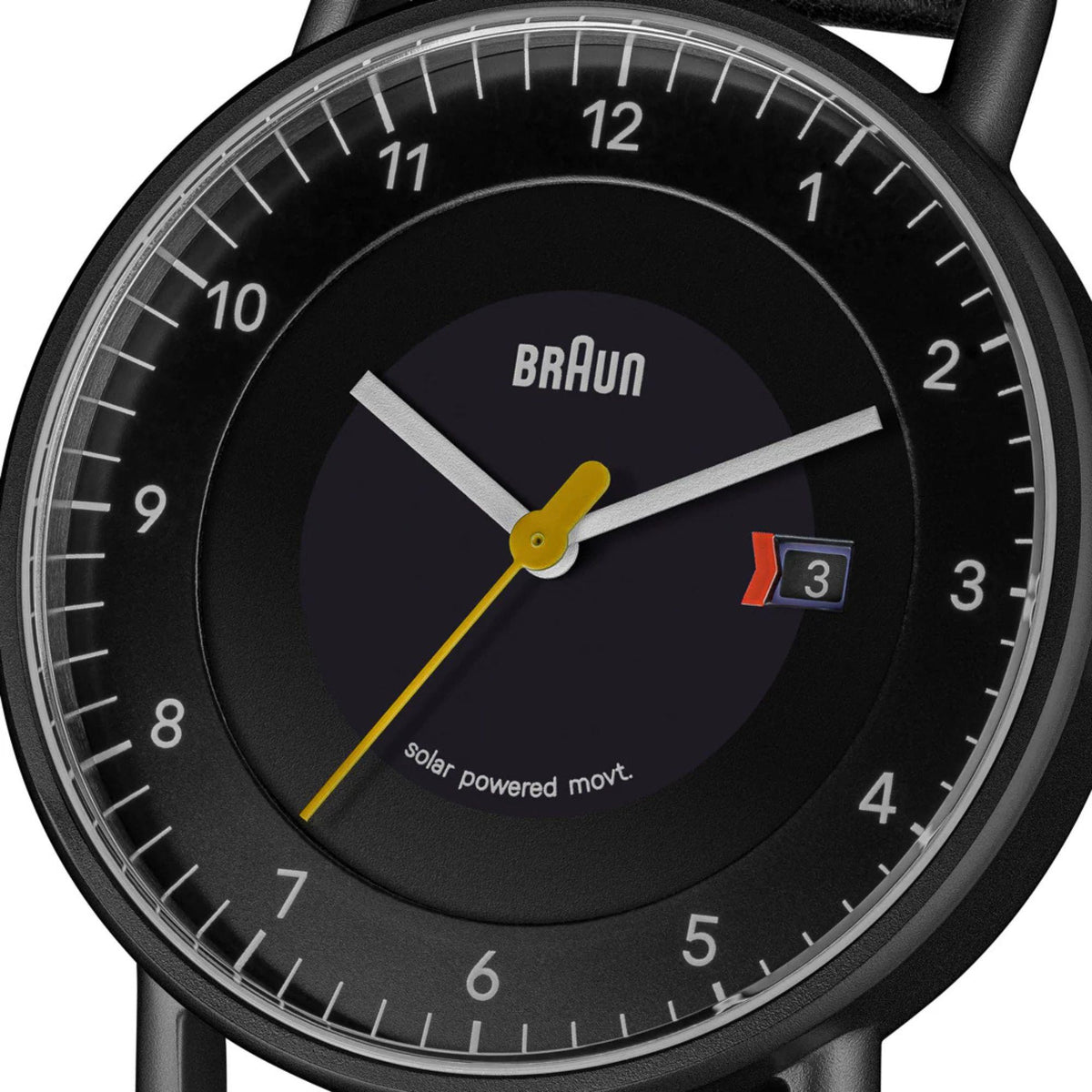 Men's solar powered watch dial close-up, BRAUN logo, date window at 3, yellow hands