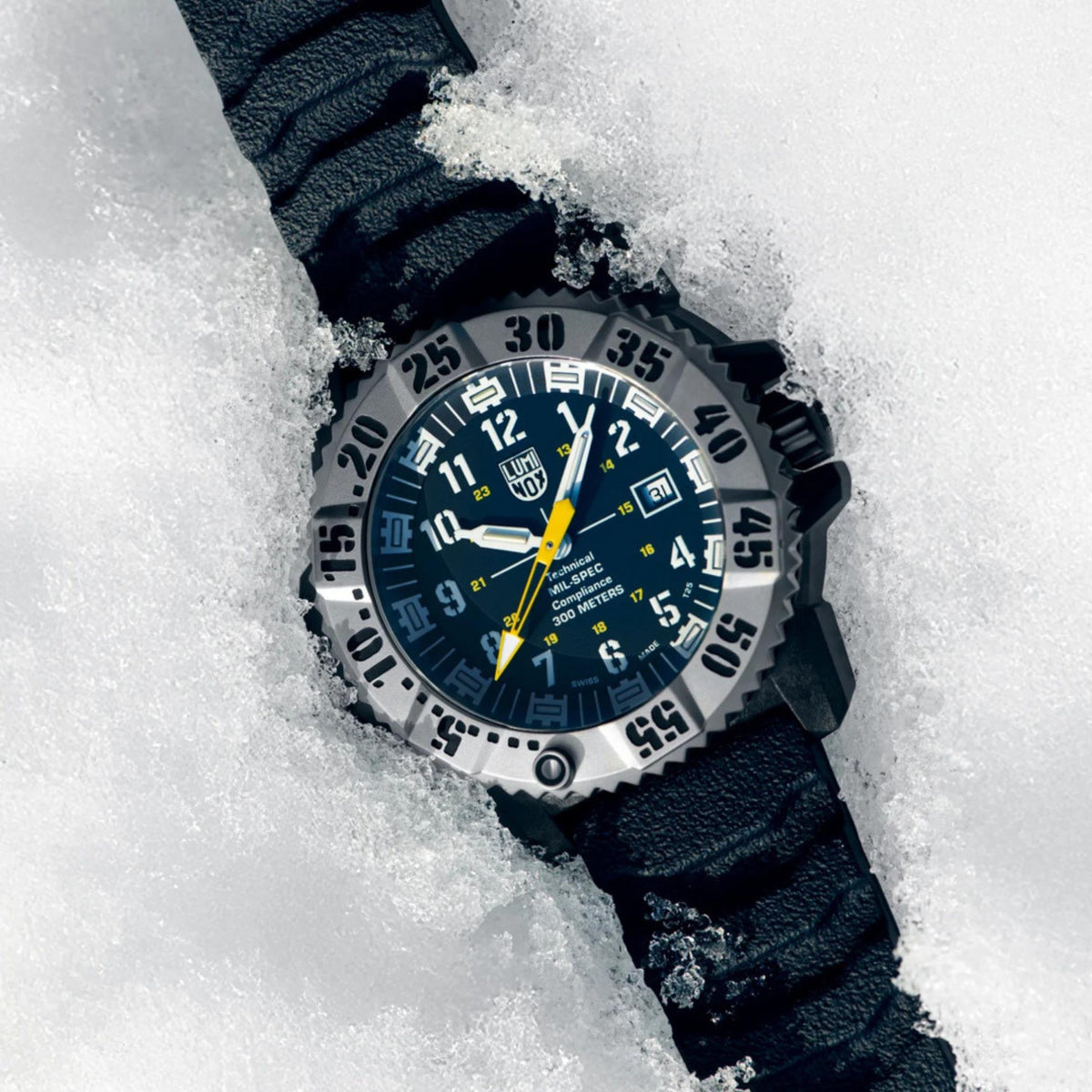 MIL-SPEC rubber watch on snow with blue dial, yellow accents, and dark blue strap