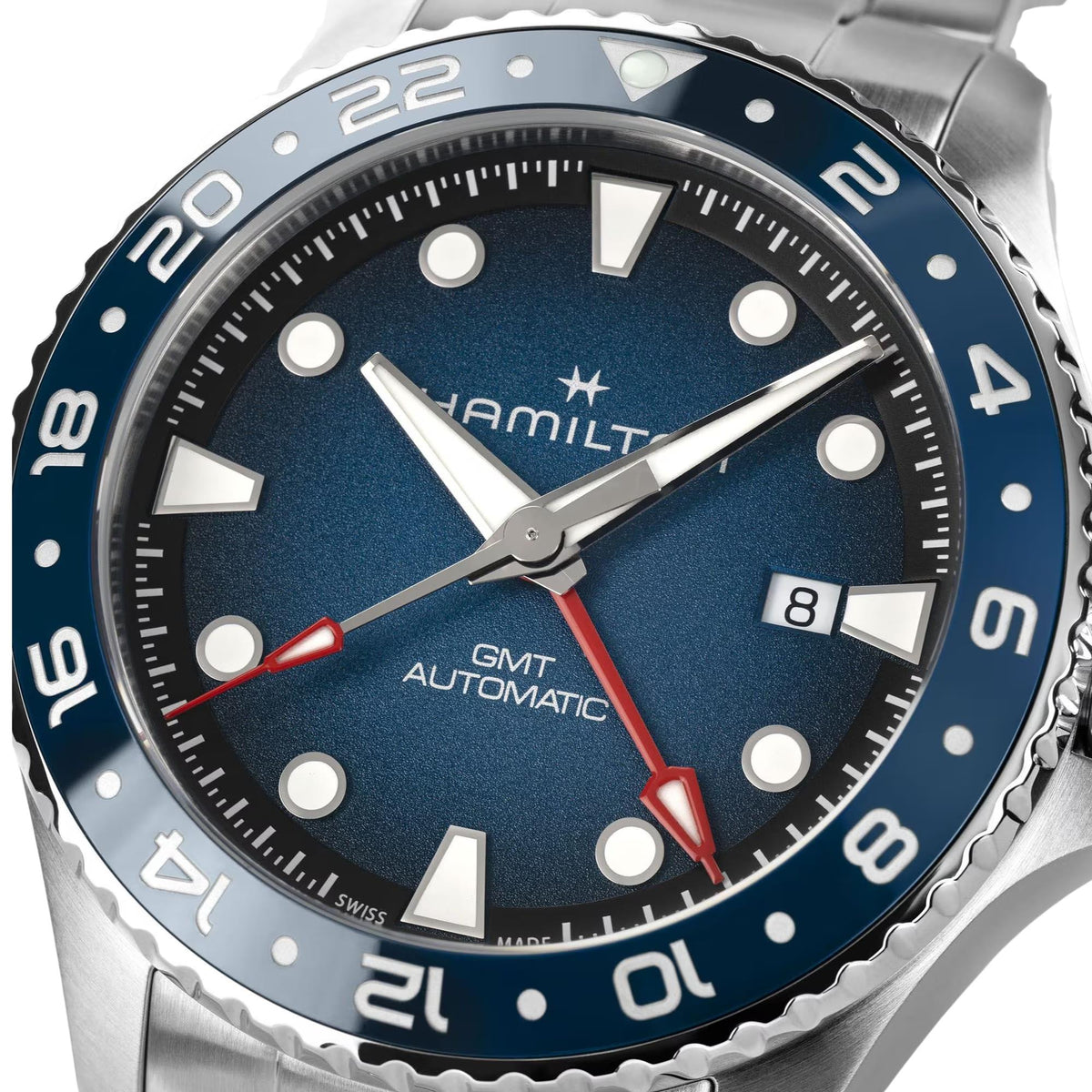 Close-up men's GMT automatic watch with blue dial, bold markers, and red GMT hand