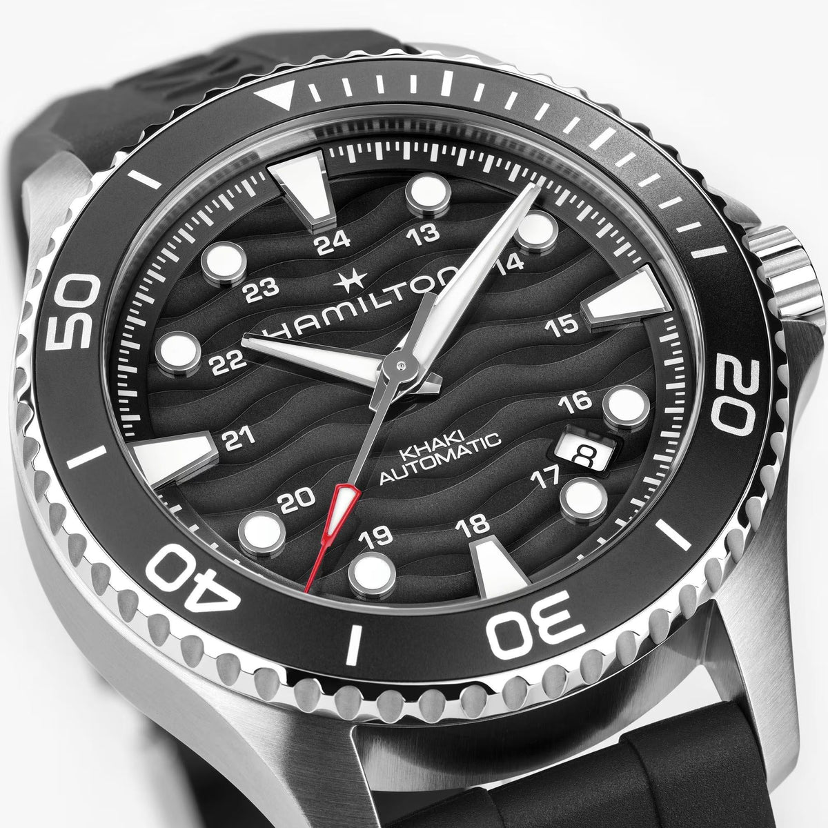 Hamilton Khaki Navy Scuba H82415330 automatic watch macro close-up highlighting black dial with wave pattern, date window, and luminous hour markers