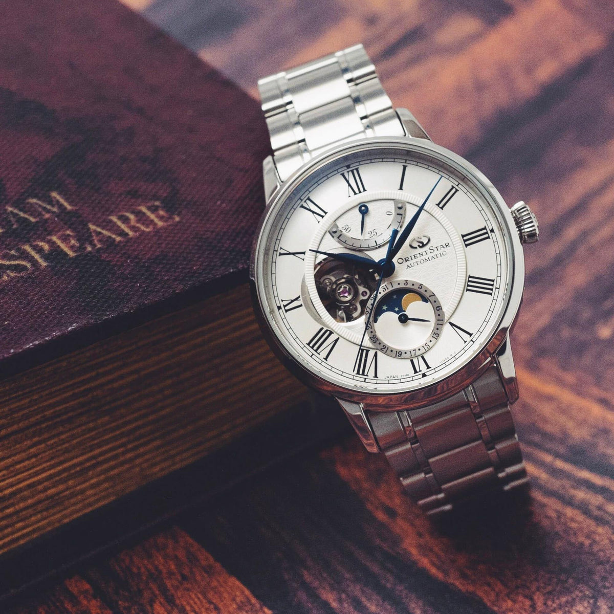 Semi-skeleton automatic watch, white dial with blue hands and moon-phase subdials, steel bracelet