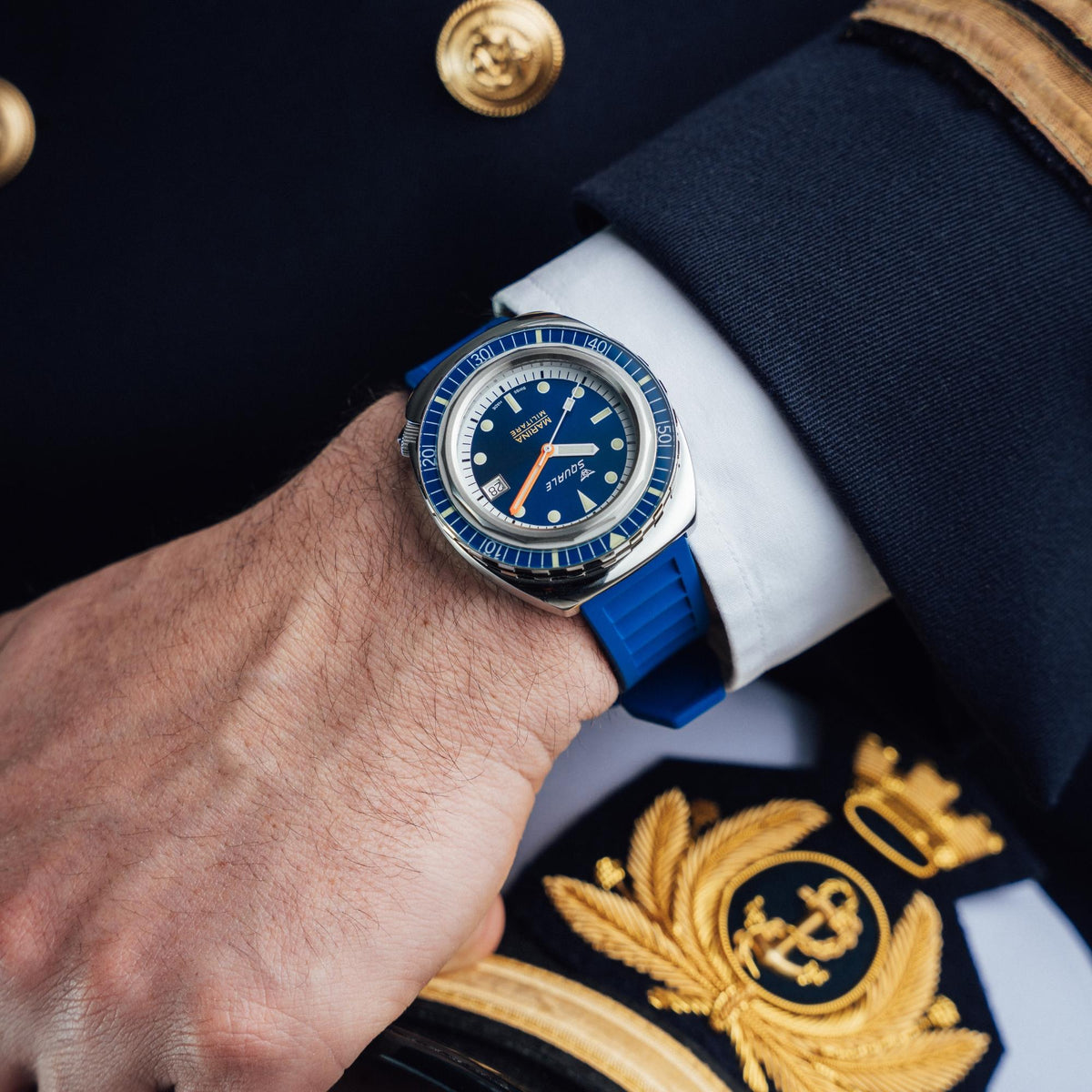Men's automatic watch on wrist with blue rubber strap and navy dial, orange second hand