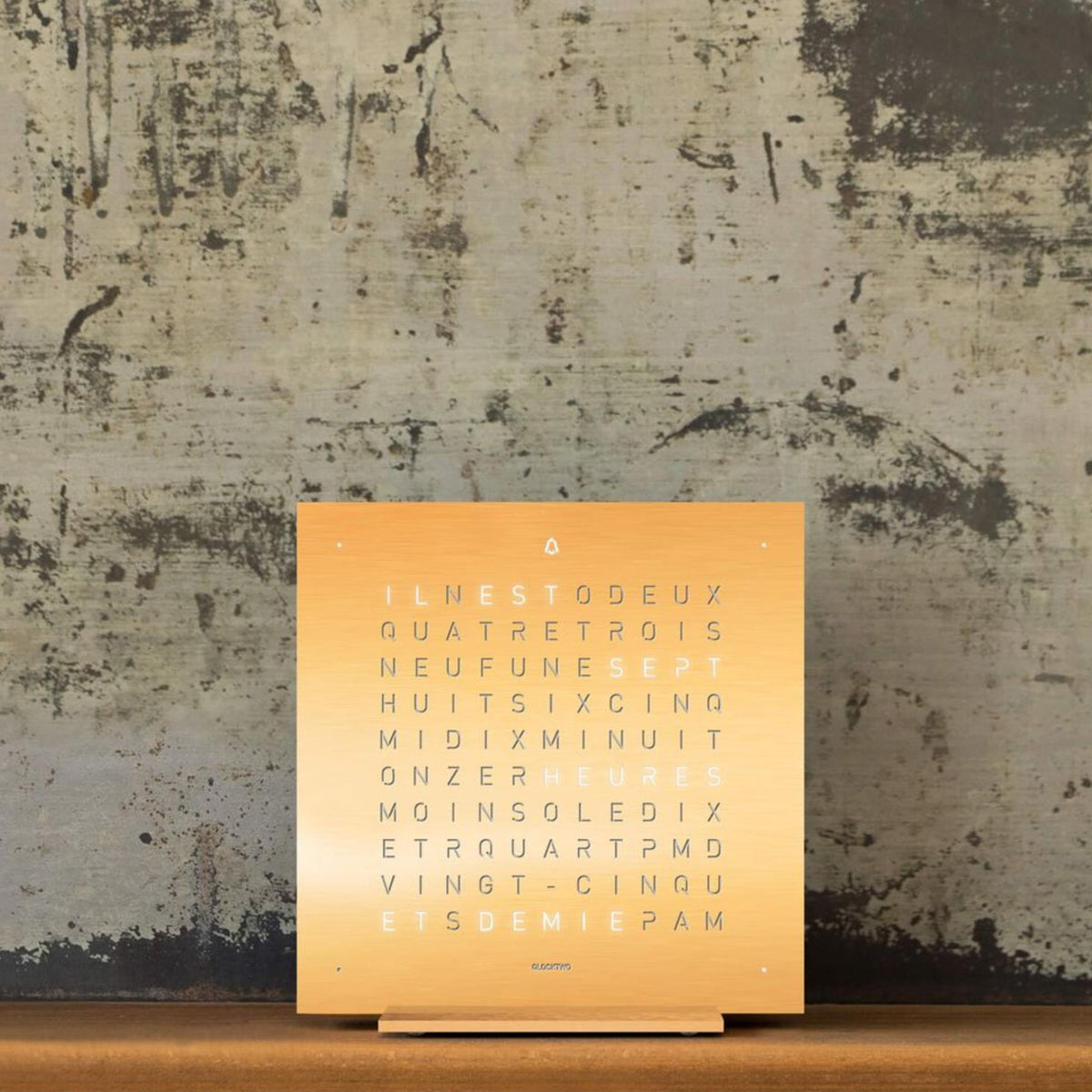 Golden word-dial table clock on display stand with illuminated letter markers
