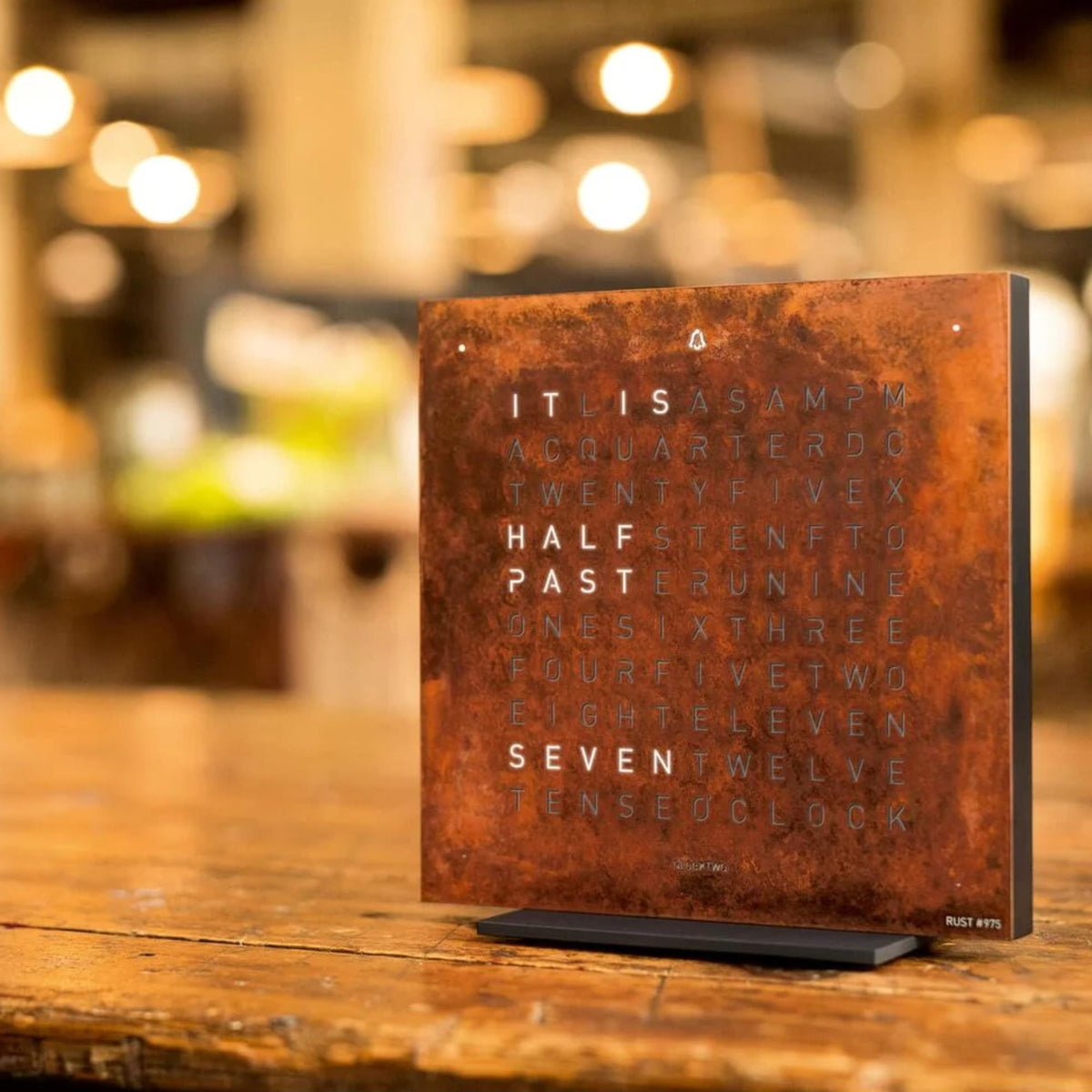Rust-brown table clock on desk with English time words illuminated on panel.