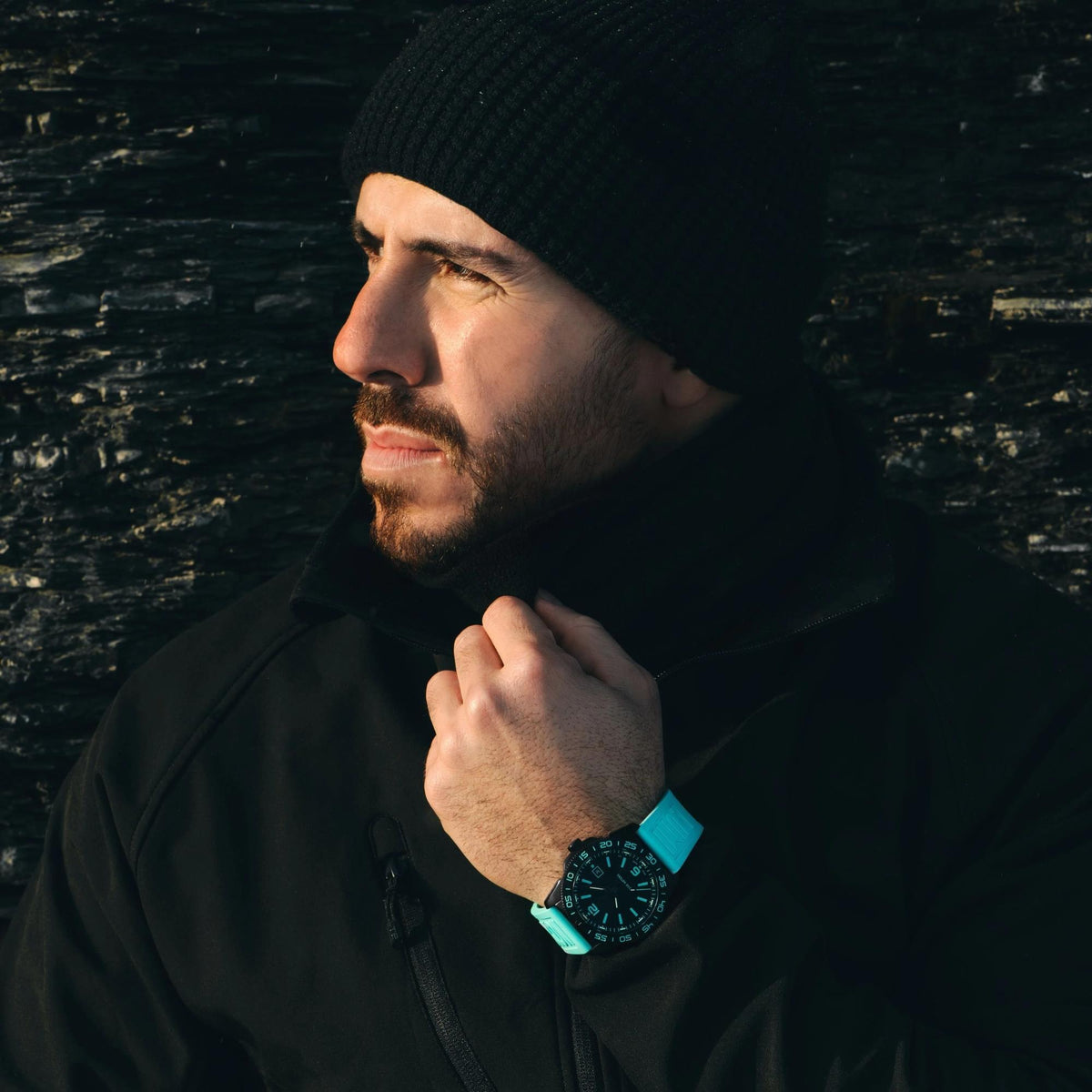Man wearing the Luminox Pacific Diver XS.3124.N.SET outdoor sports watch with a turquoise rubber strap and dark jacket