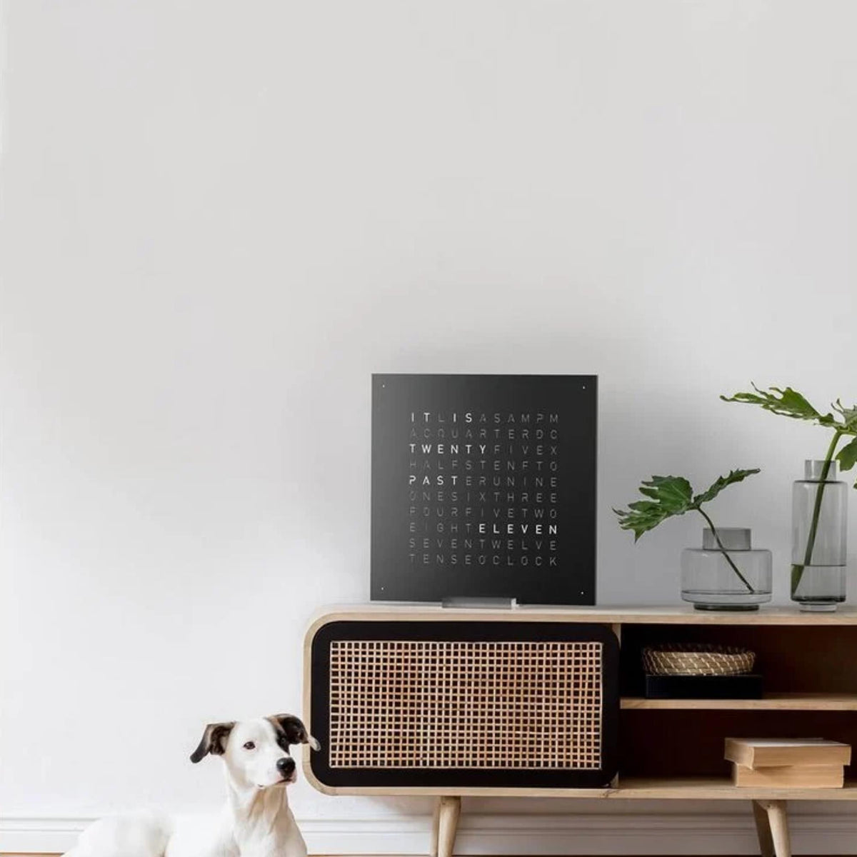 Black pepper QLOCKTWO wall clock on wall with lit hour word dial