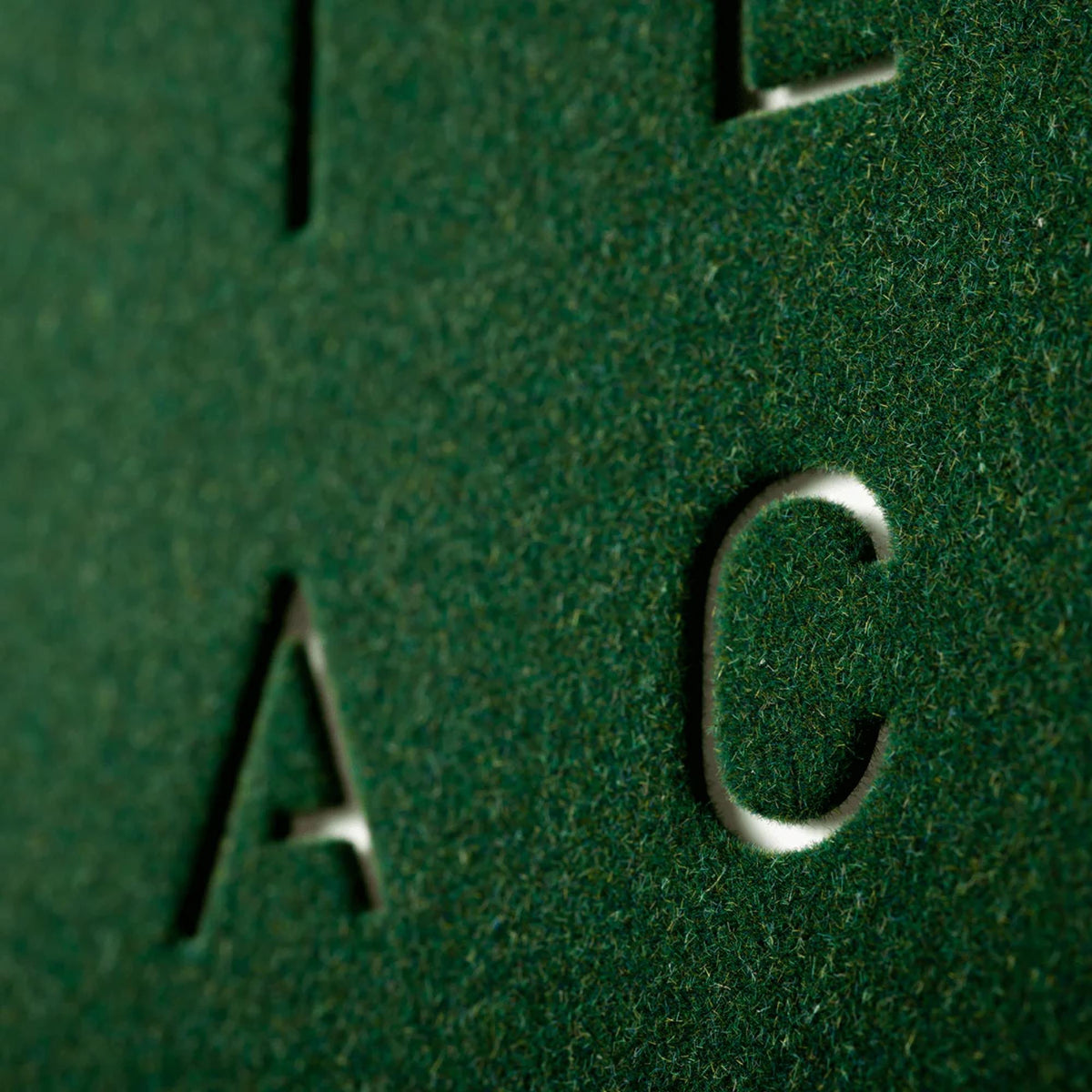 Green velvet word-clock panel close-up showing letter C cutout