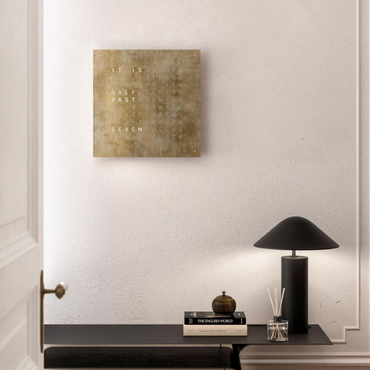 QLOCKTWO wall clock with gold square dial and English letter lines on wall