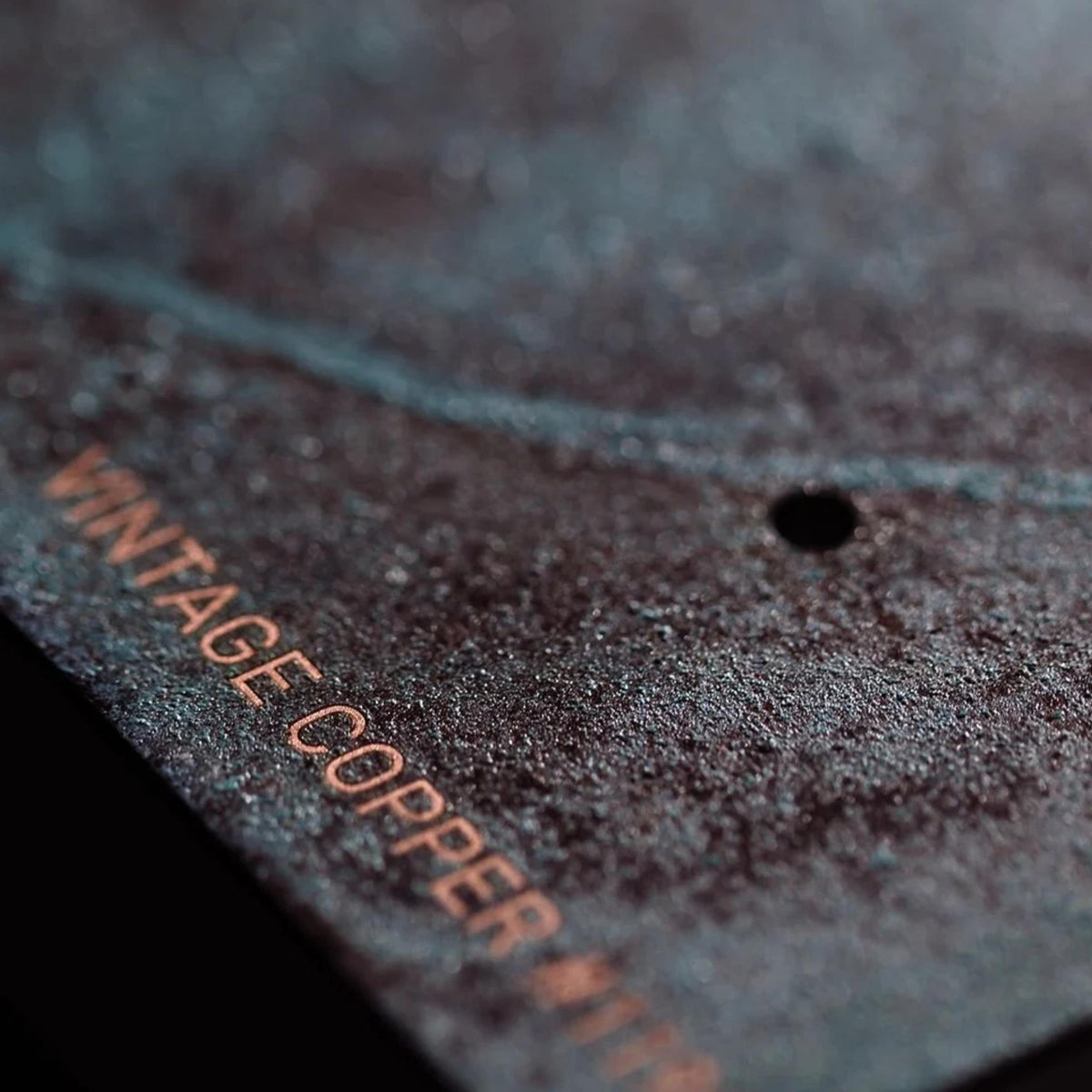 Close-up of teal clock face with copper-toned 'MAMTHAGCORD COPPER' engraving