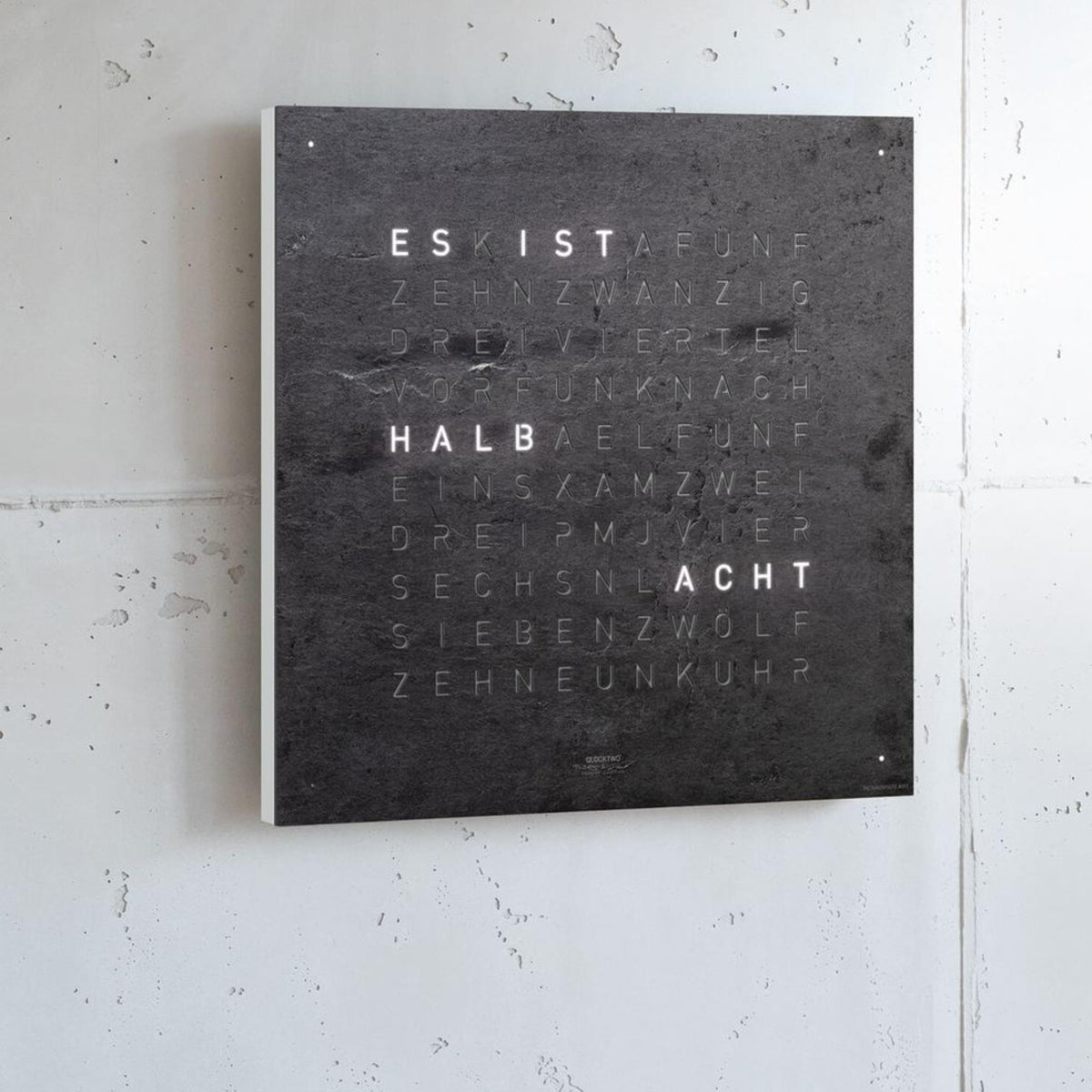 Square wall clock with dark slate face and engraved text rows with glowing highlight