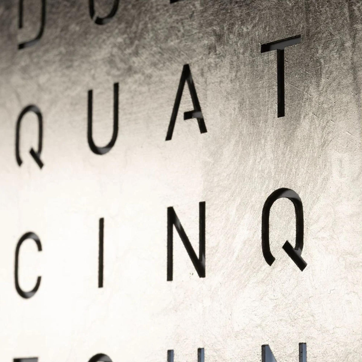 Close-up of raised English letter numerals on a platinum wall clock face