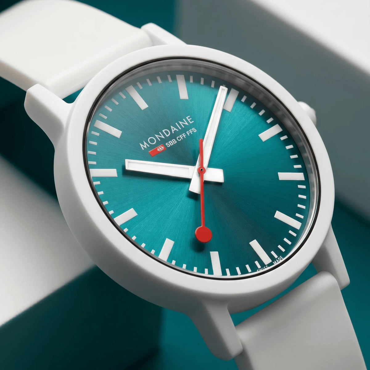 Teal dial watch with white hour markers and red-accent hands, close-up