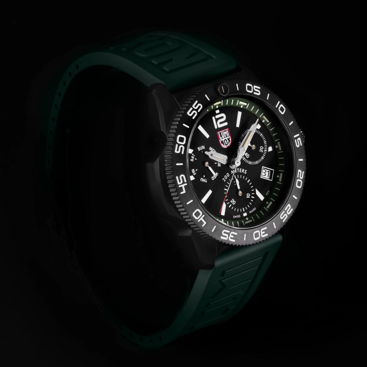 Men's diver chronograph watch in low light, black dial with green bezel, rubber strap