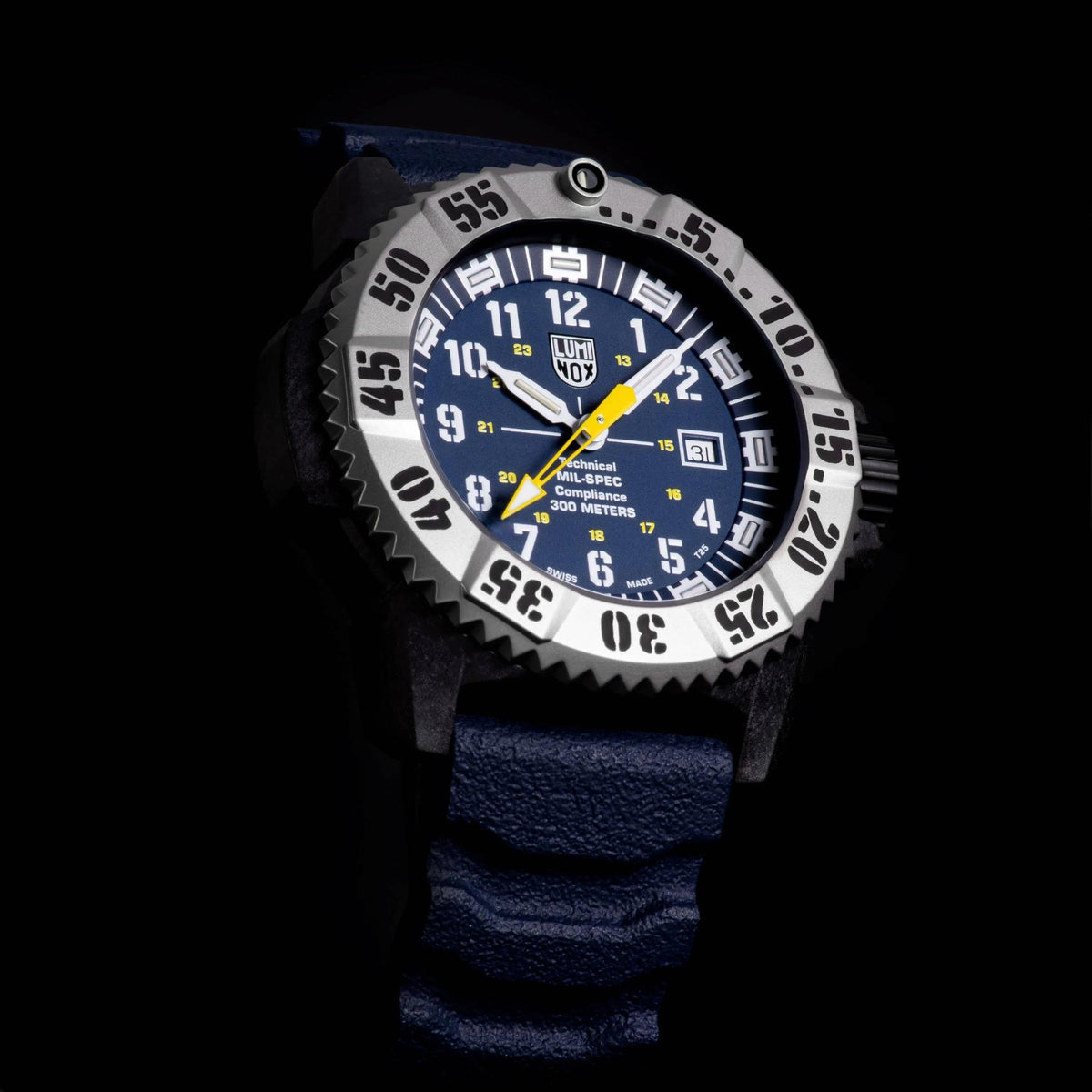 Men's quartz dive watch with blue dial, silver bezel, and dark navy rubber strap in dark setting.