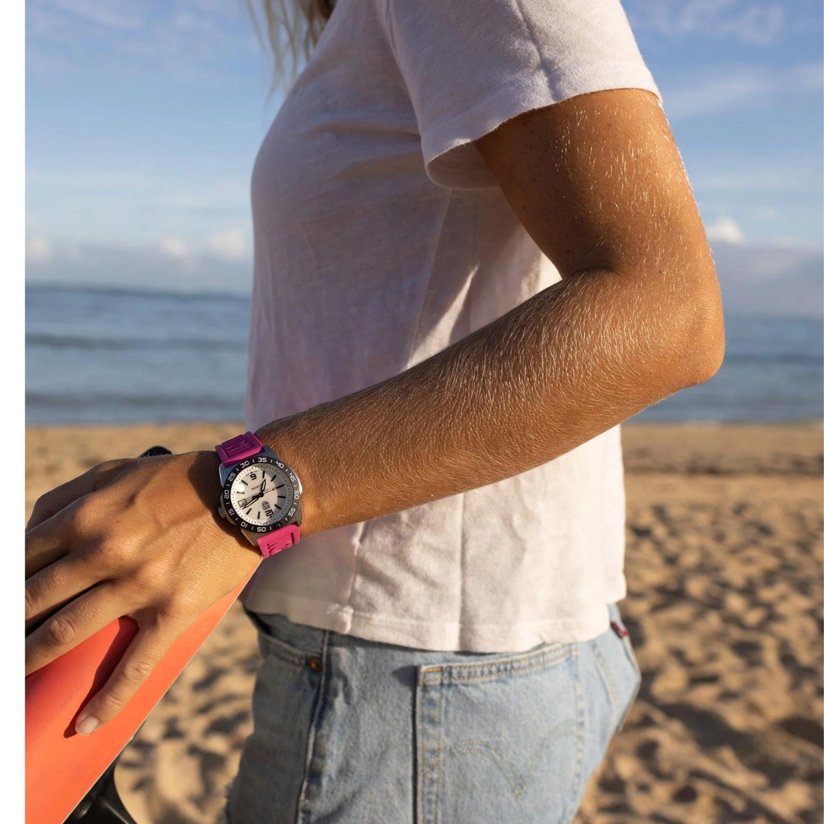 Diver watch with white dial and black bezel, pink rubber strap on an arm
